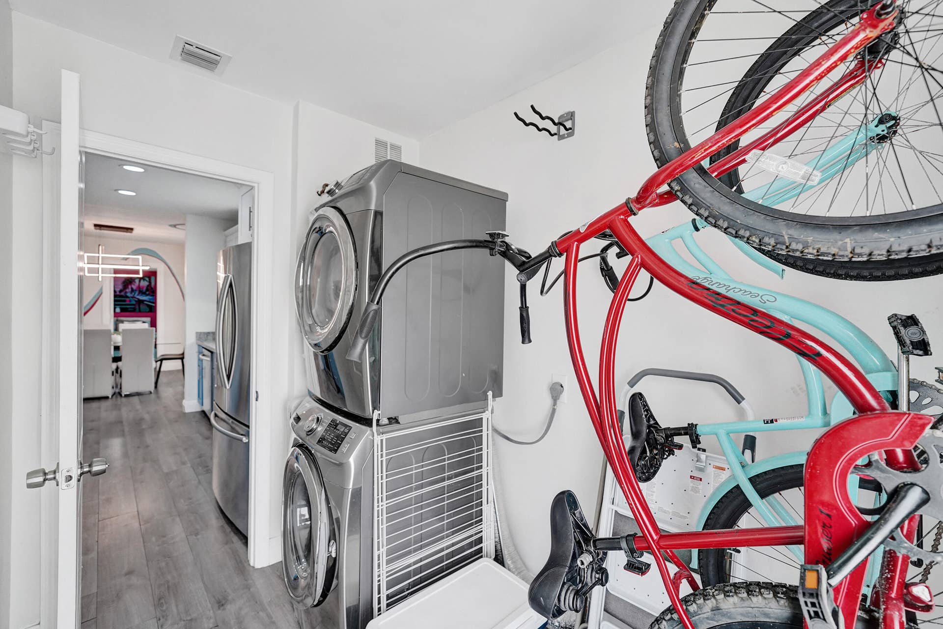 Stackable washer and dryer unit, wood-finish flooring, and a door leading to an interior space