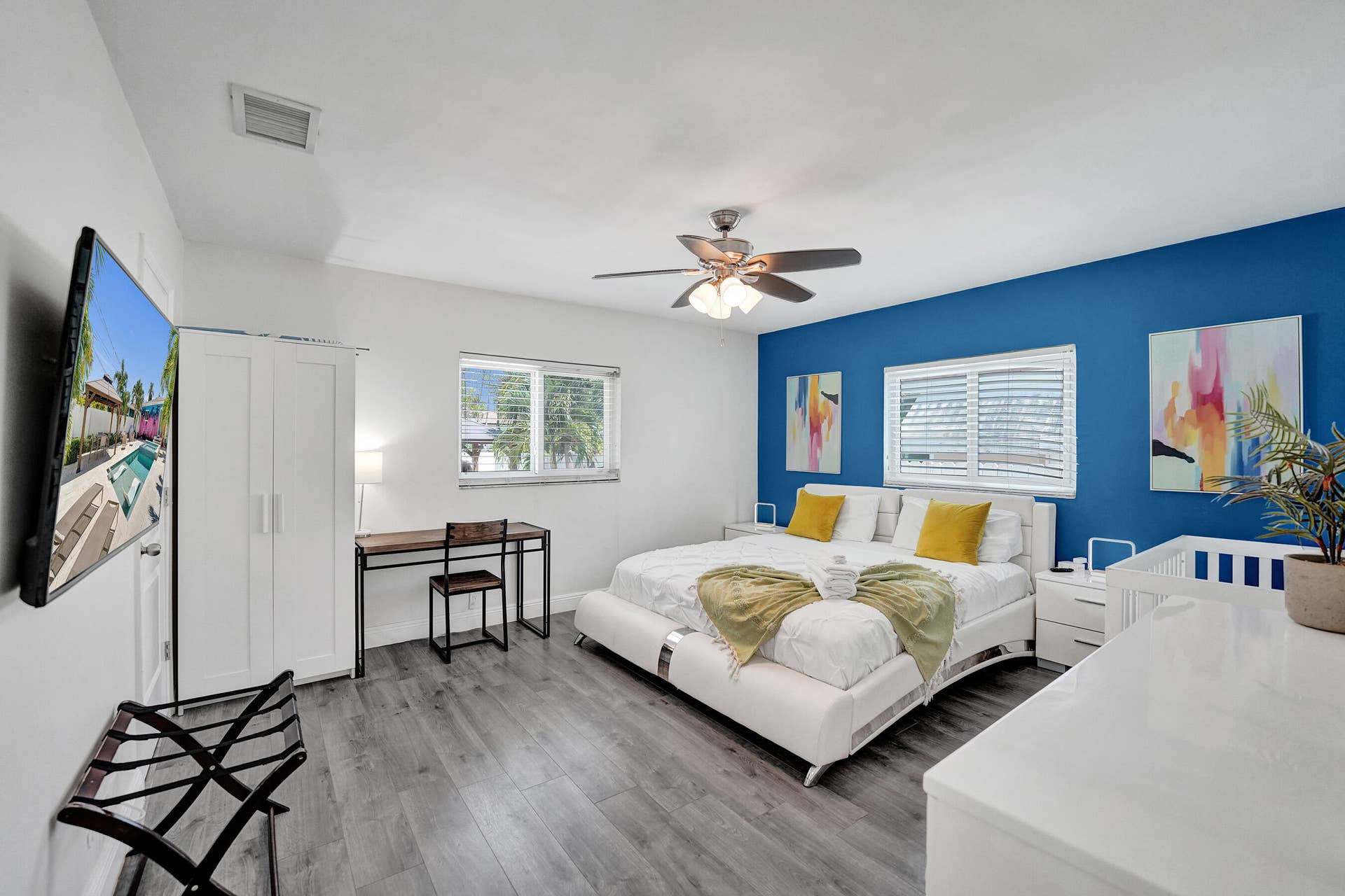 Wood-finish flooring, ceiling fan, white window shutters, and a prominent accent wall