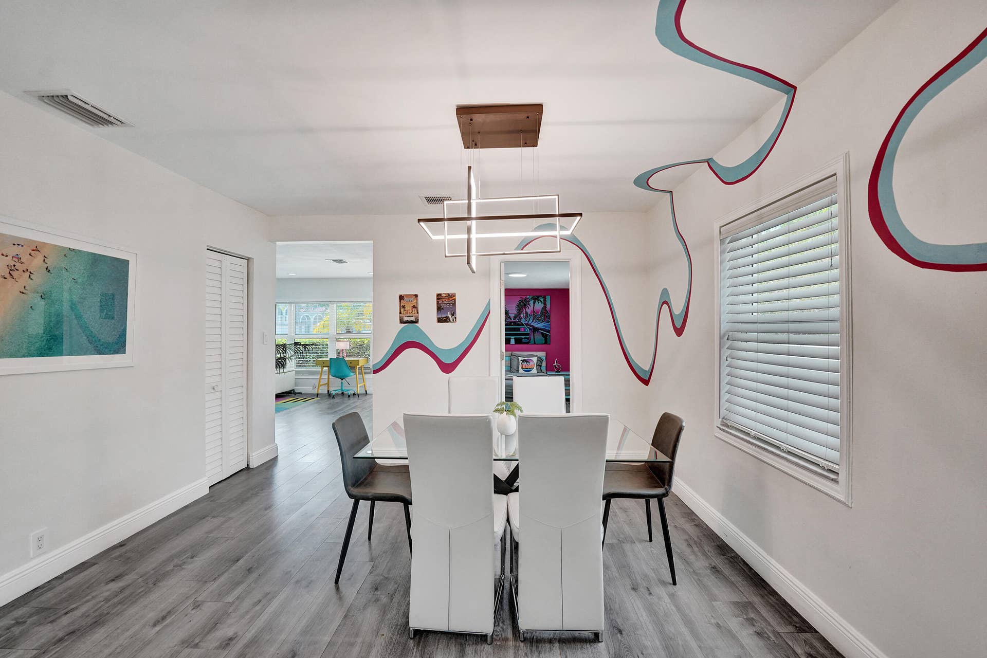 Wood-finish flooring, contemporary chandelier, custom wall art, and a large window with blinds