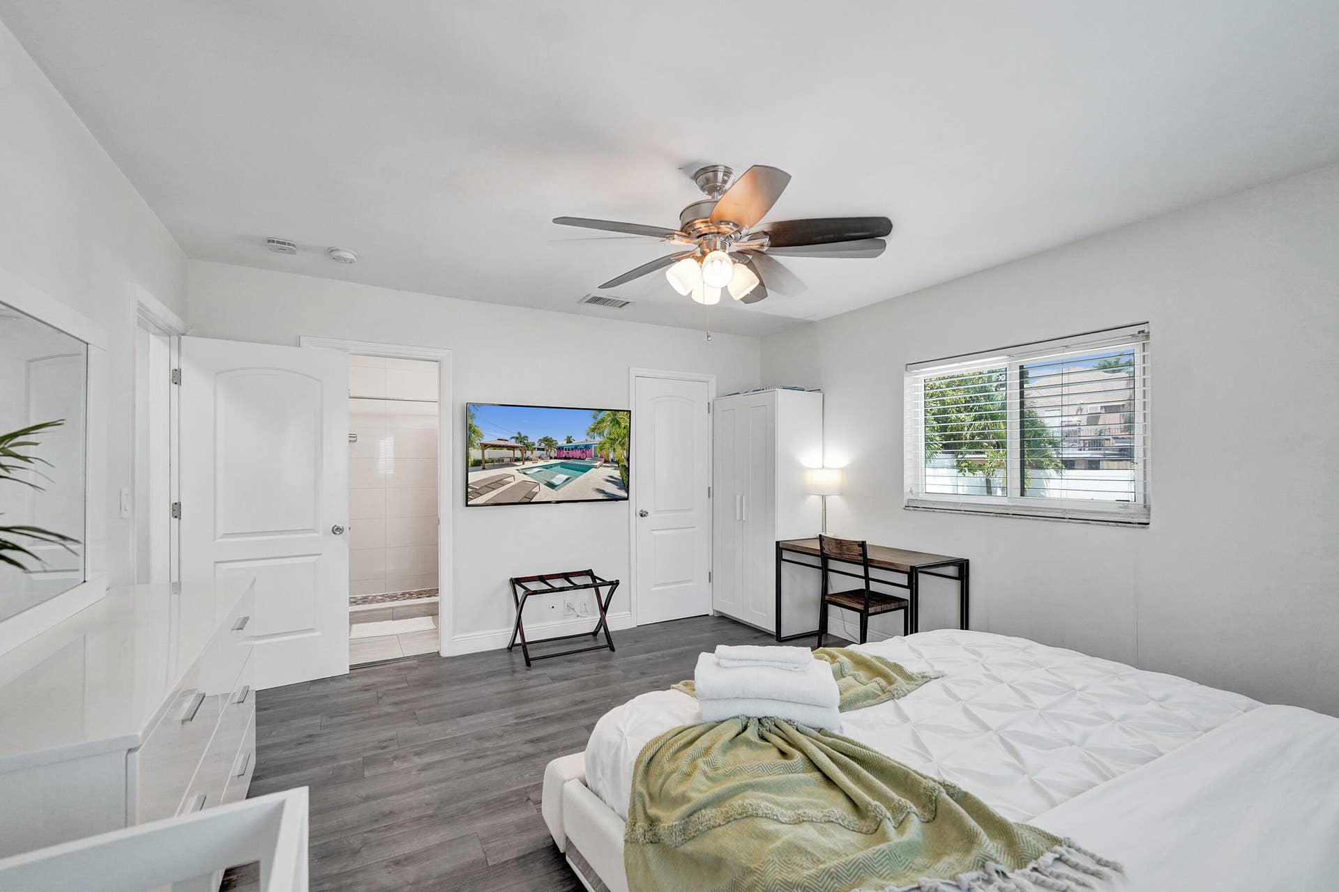 Spacious room featuring wood-finish flooring, a ceiling fan with integrated lighting, and white paneled doors