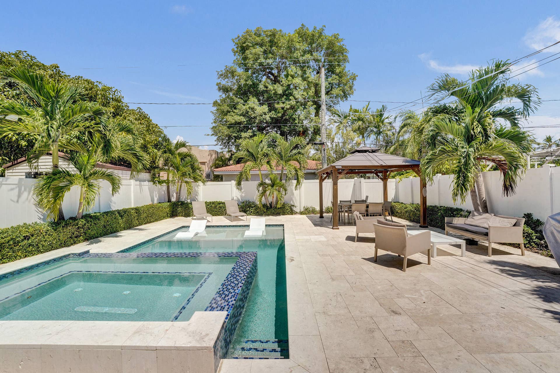 Expansive outdoor patio featuring a swimming pool, integrated spa, and an attached gazebo