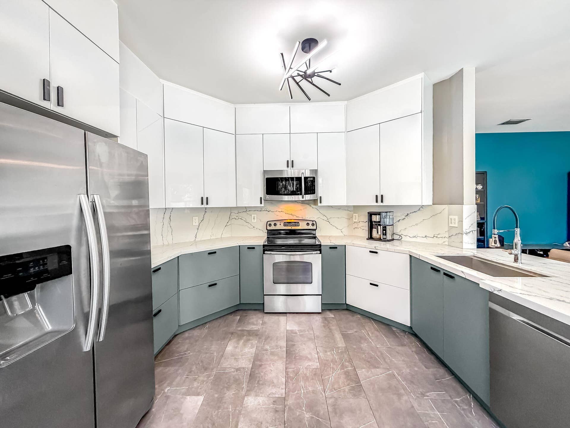 18980 CONCERTO Drive, Boca Raton, FL 33498 Curved kitchen featuring stainless steel appliances, two-tone cabinetry, a decorative ceiling light fixture, and an undermount sink