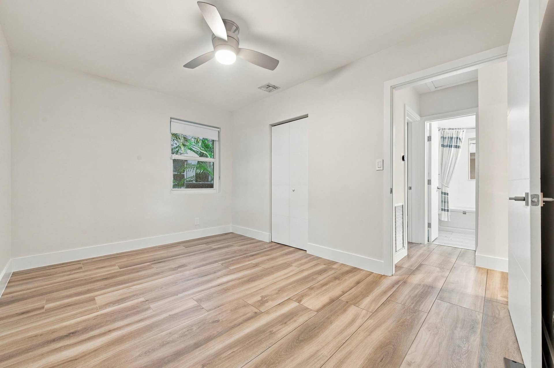 Wood-finish flooring, white walls, and a ceiling fan with integrated lighting