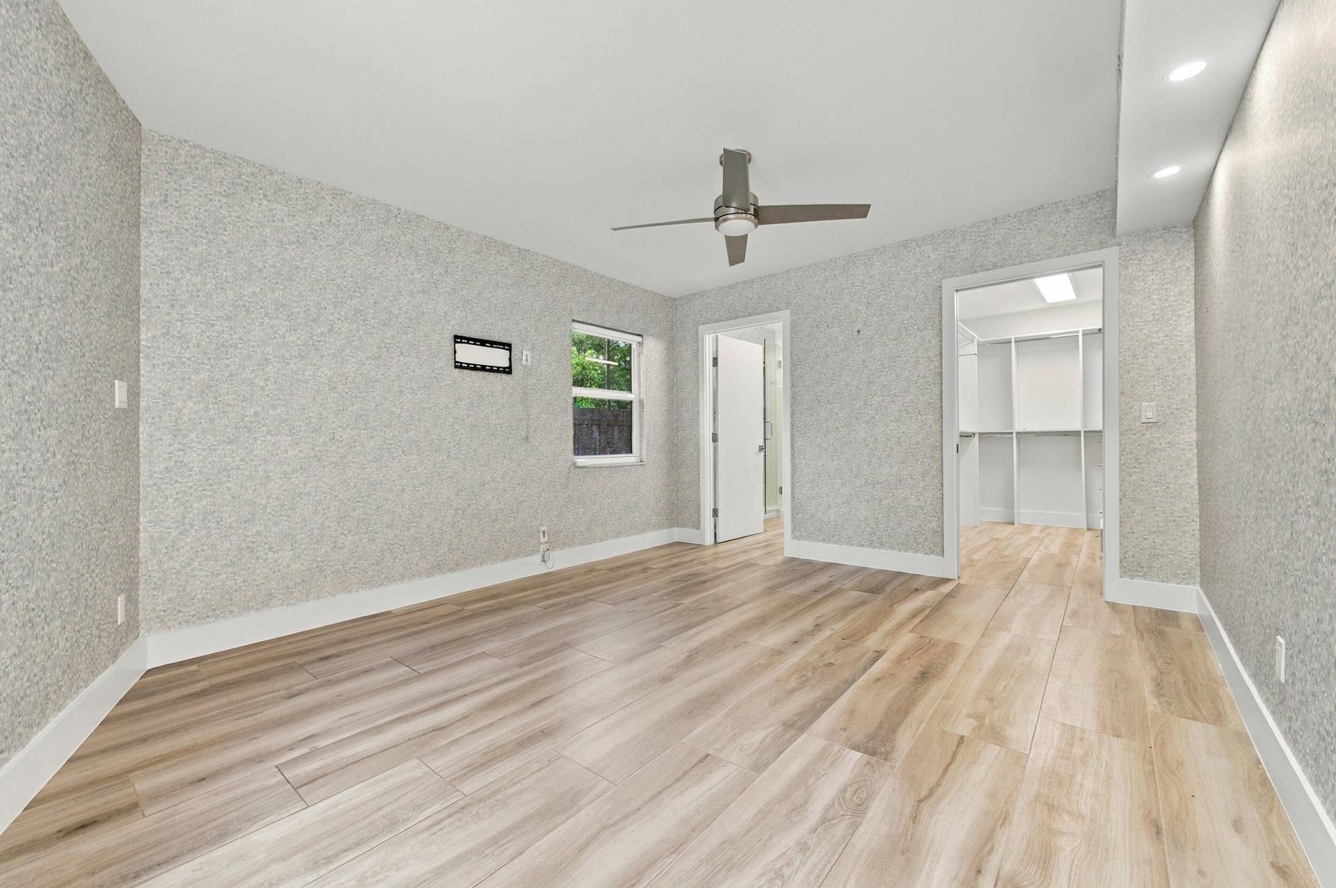 Wood-finish flooring, textured wall finishes, a ceiling fan, recessed lighting, and a walk-in closet with built-in shelving