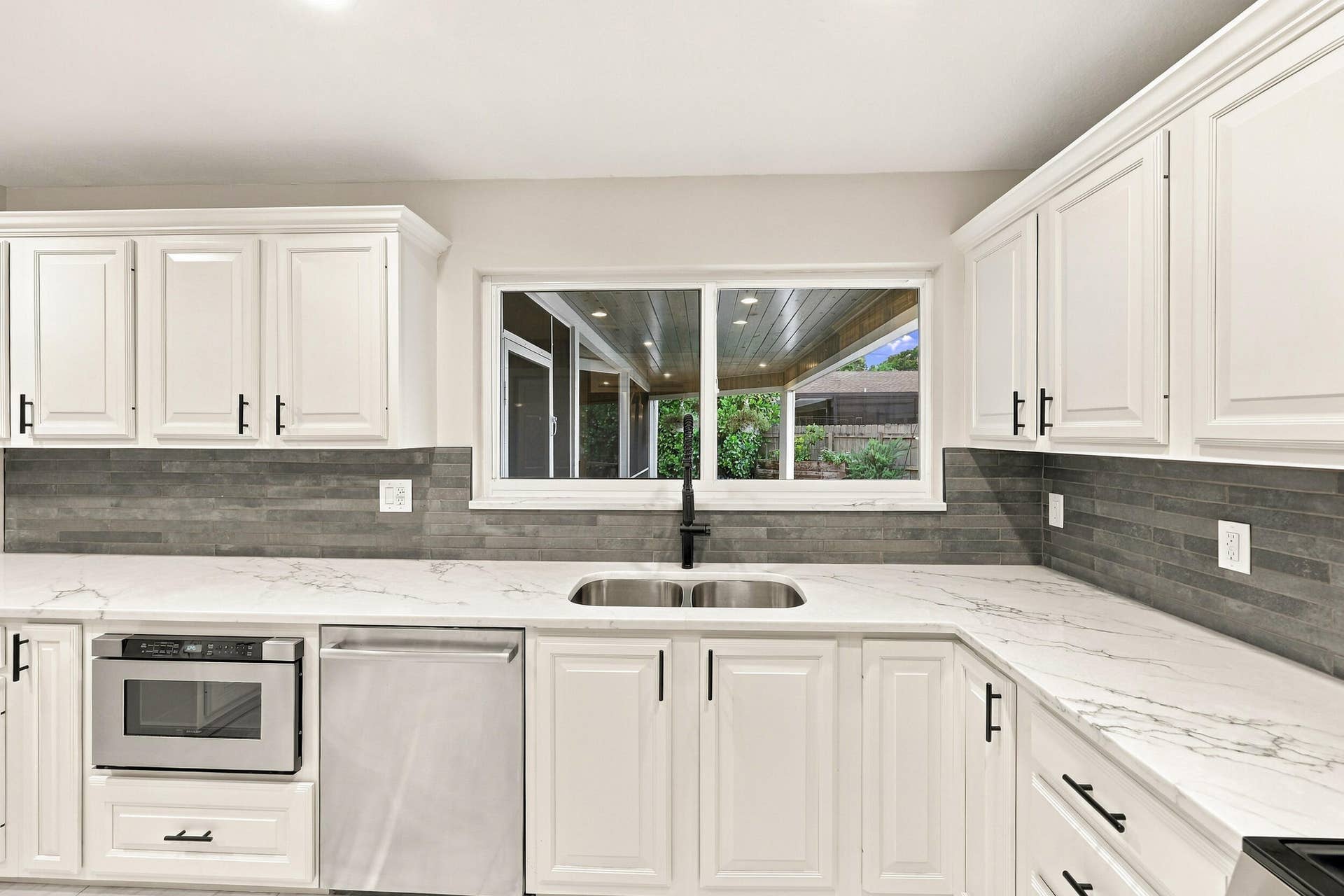 3590 Lakeview Drive, Delray Beach, FL 33445 From the kitchen sink, you can admire the resort-style pool, spacious backyard, and 900-square-foot covered and screened-in patio.