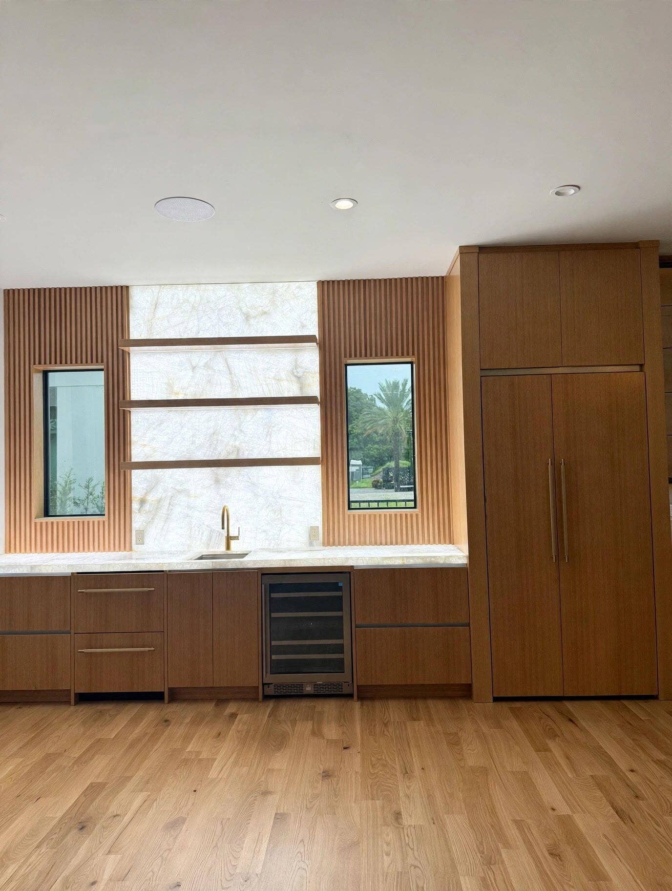 1109 PROSPERITY VILLAGE Drive, North Palm Beach, FL 33410 Wood-finish cabinetry with integrated appliances, light-toned countertop, and wood-finish flooring
