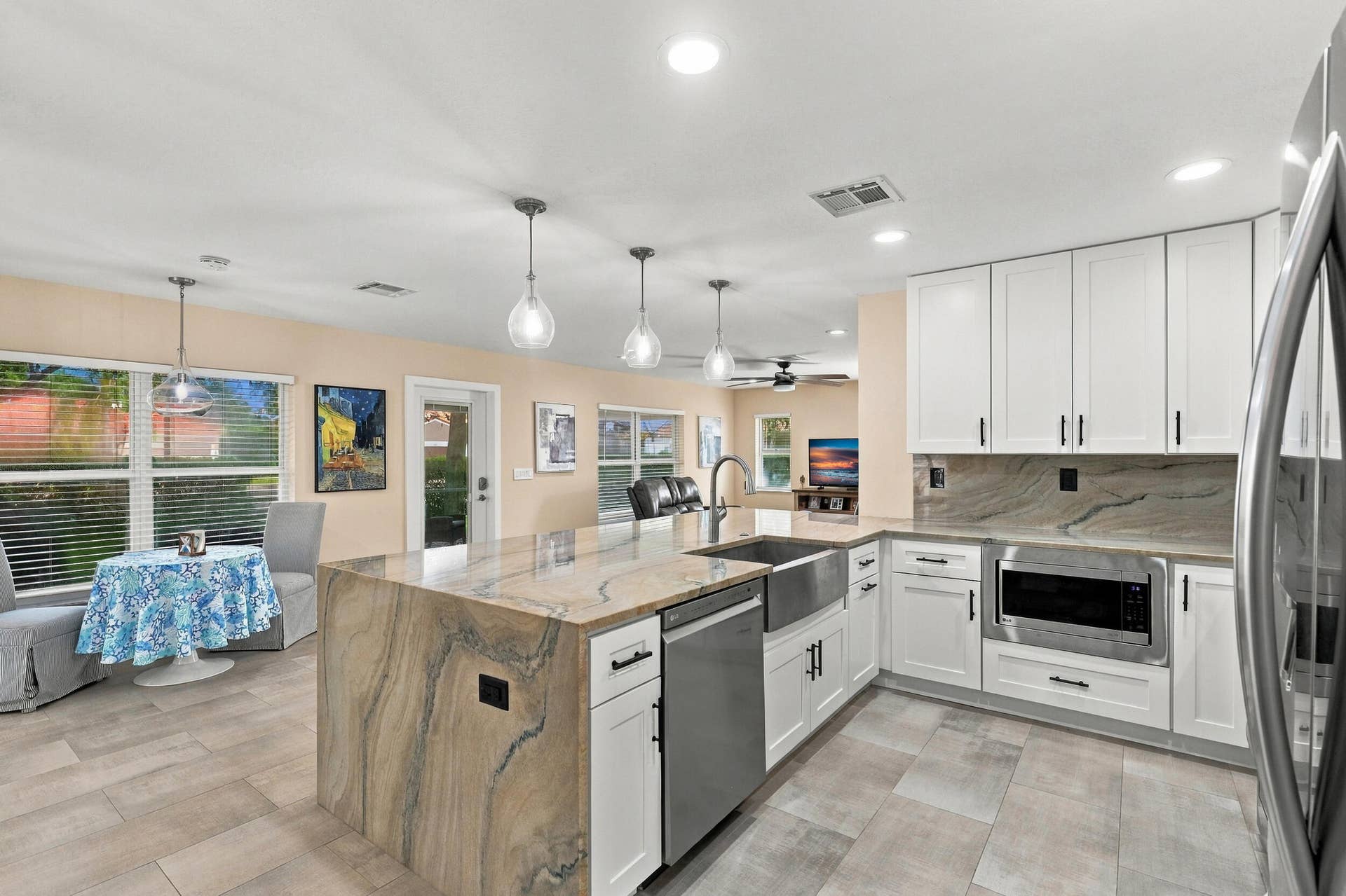 1434 Artimino Lane, Boynton Beach, FL 33436 The heart of the home is the exquisite renovated kitchen, featuring white Shaker style cabinetry, stunning quartzite countertops and backsplash, stainless steel appliances, designer lighting, abundant storage, and an oversized island that creates an impressive centerpiece for everyday living and entertaining. The open layout flows effortlessly into the main living areas and breakfast nook, while a separate dining space provides plenty of room for gatherings.