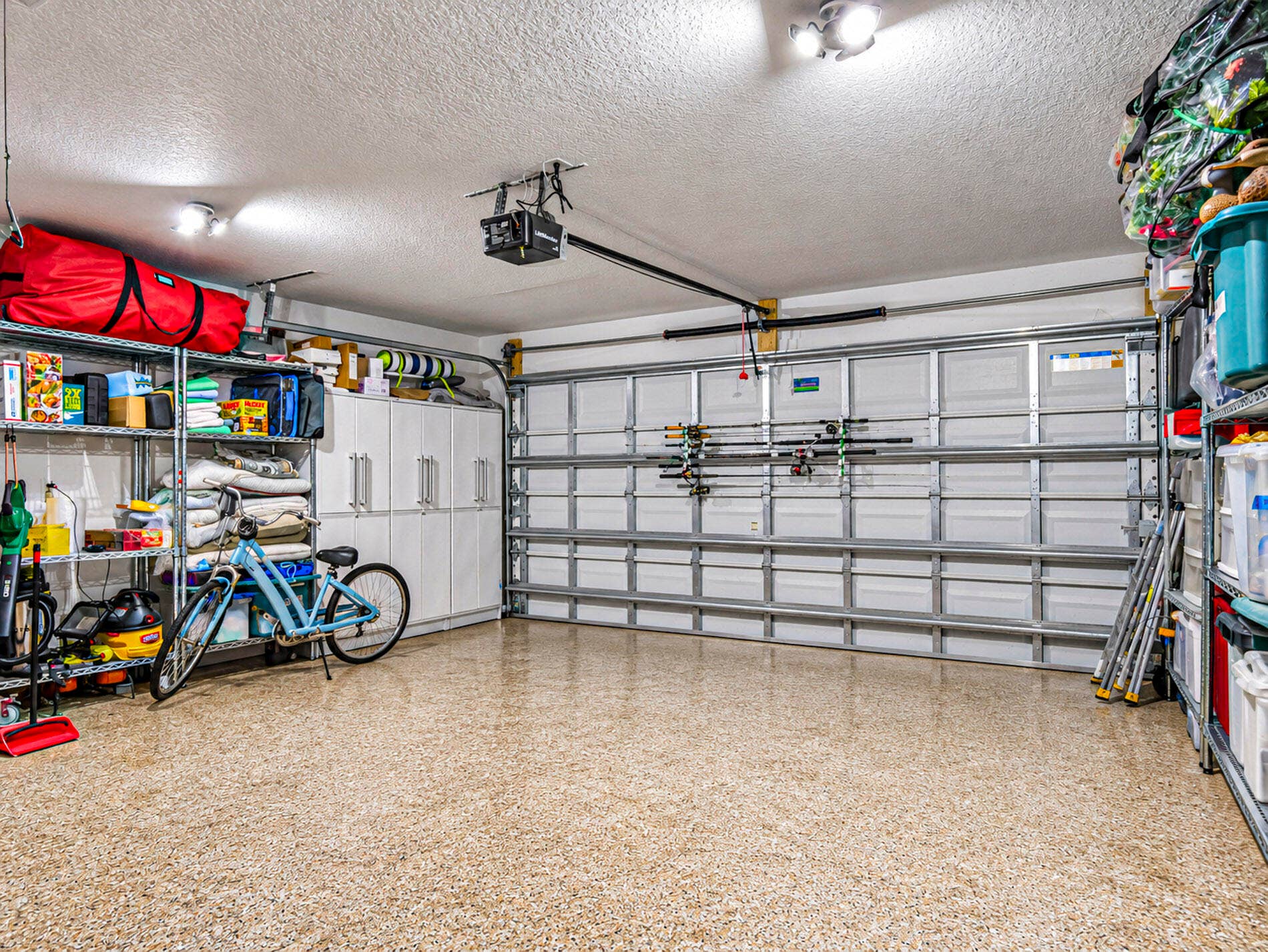 215 8TH Terrace, Vero Beach, FL 32962 Garage space featuring a speckled epoxy floor, built-in white cabinetry, metal shelving units.