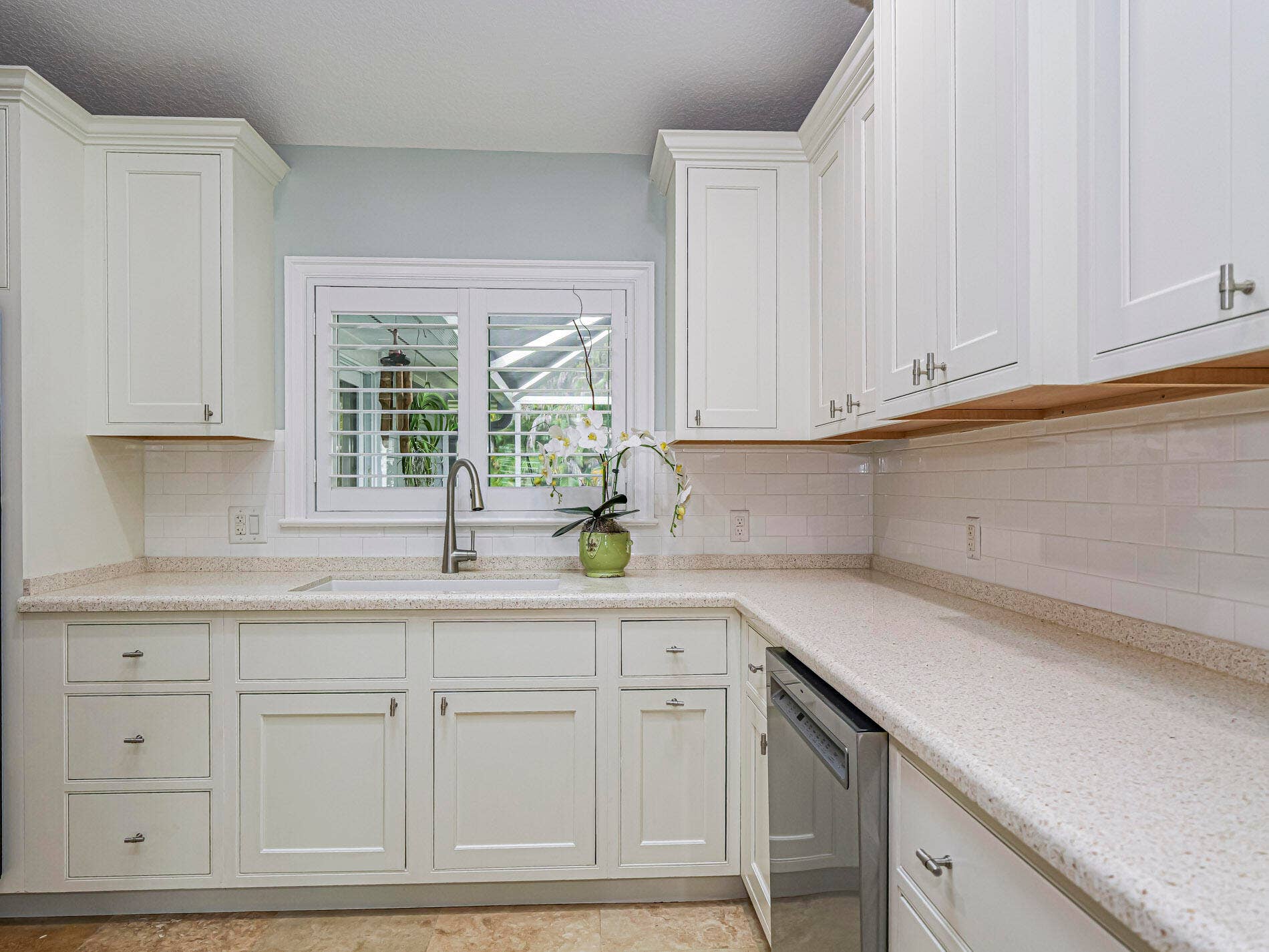 215 8TH Terrace, Vero Beach, FL 32962 White shaker-style cabinetry, light-granite subway tile backsplash.