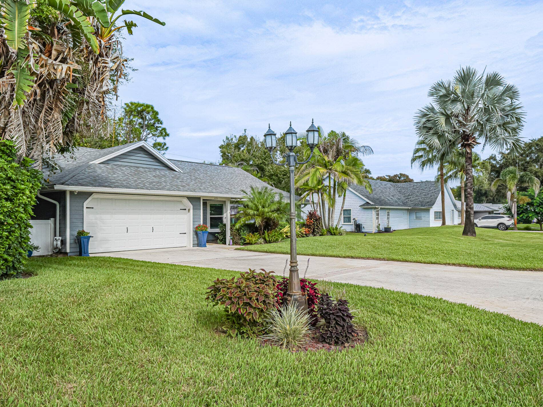 215 8TH Terrace, Vero Beach, FL 32962 Manicured lawn, mature landscaping, a concrete driveway.