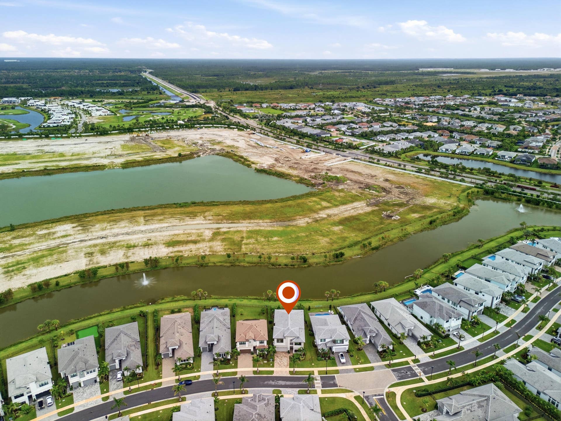 Aerial perspective of a residential community featuring waterways, established homes, and undeveloped land