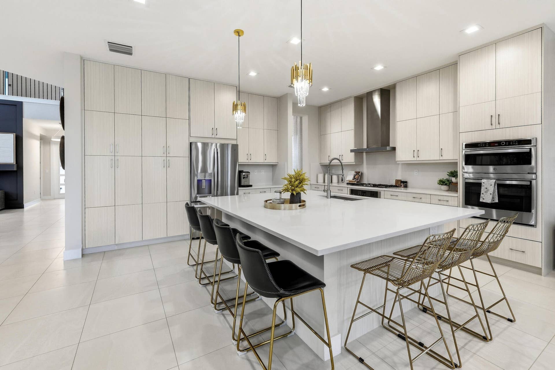 Gourmet kitchen featuring a substantial island with countertop, stainless steel appliances, extensive cabinetry, tile flooring, and integrated pendant lighting