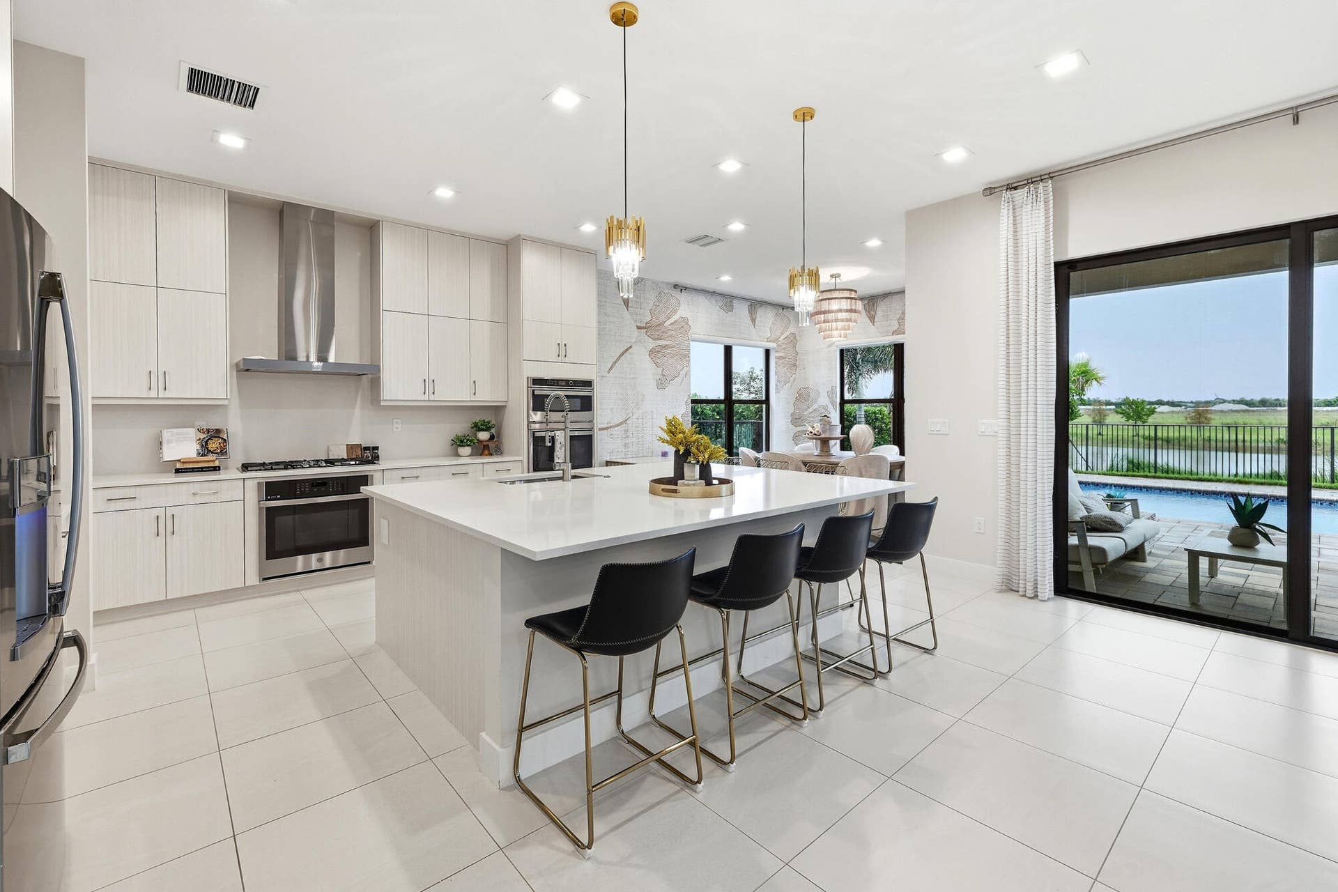 Modern kitchen featuring light-toned cabinetry, stainless steel appliances, a large center island with seating, and tile flooring