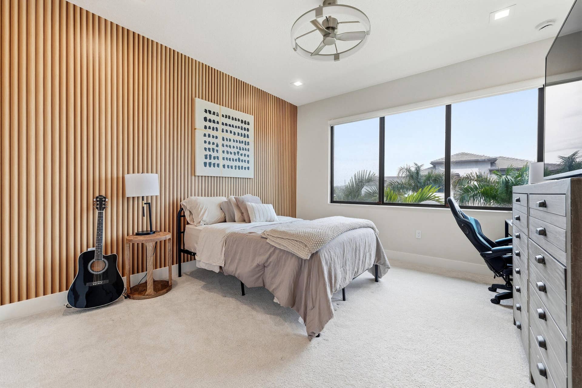 Wood-slat accent wall, large picture windows, recessed lighting, ceiling fan, and light-toned carpeting