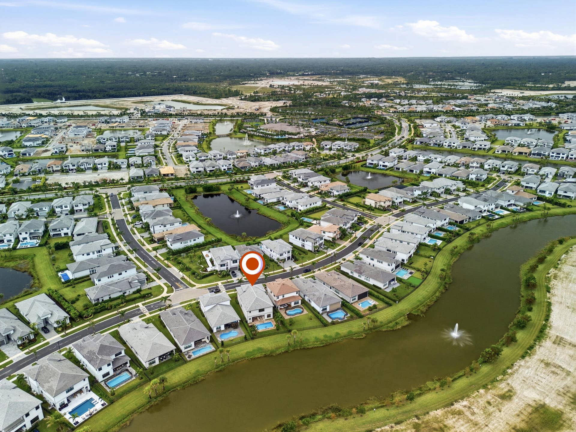 Residential community featuring a curved street pattern, multiple ponds with fountains, and an expansive surrounding greenbelt