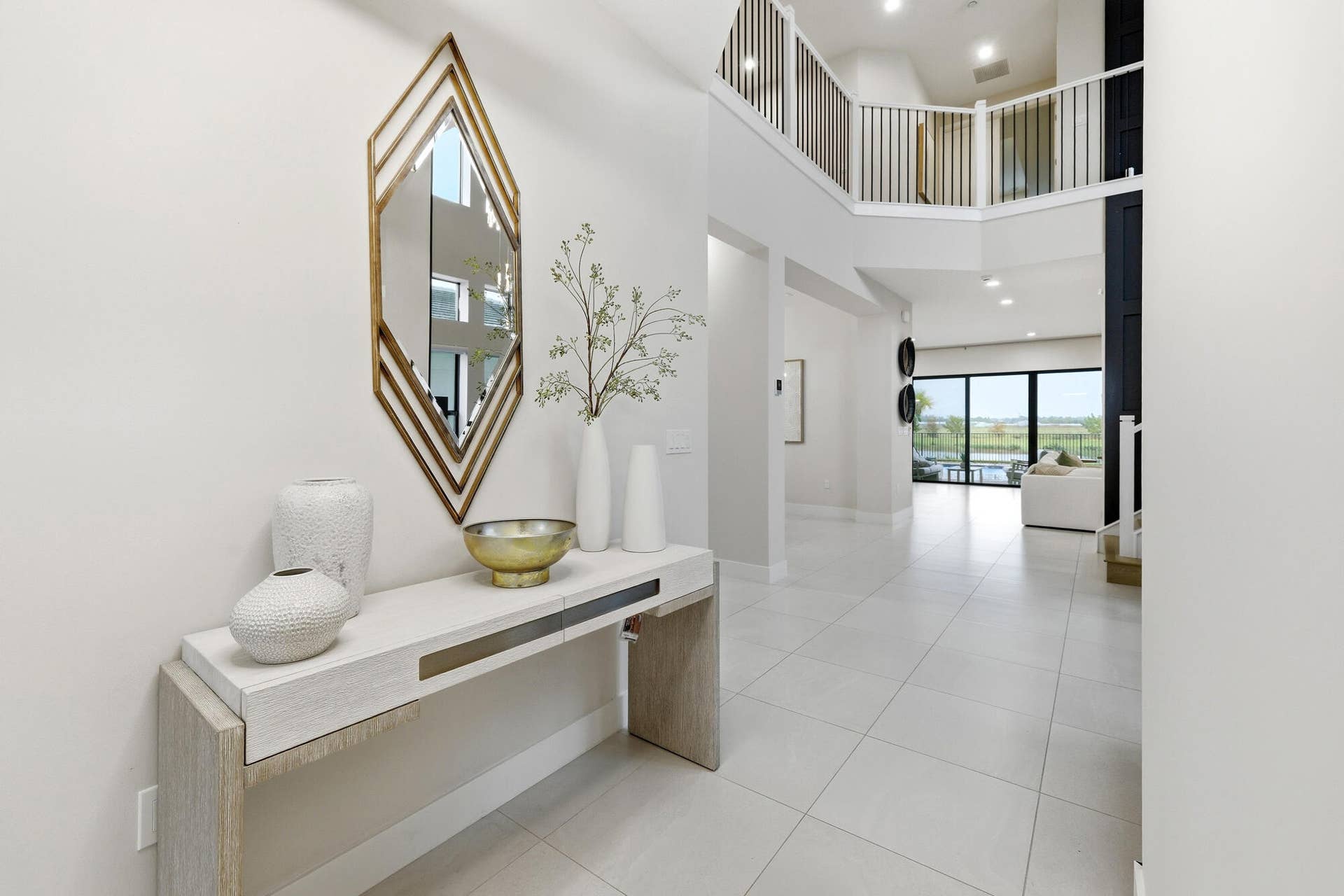 Two-story entry foyer featuring large format tile flooring and a second-story balcony with metal railings