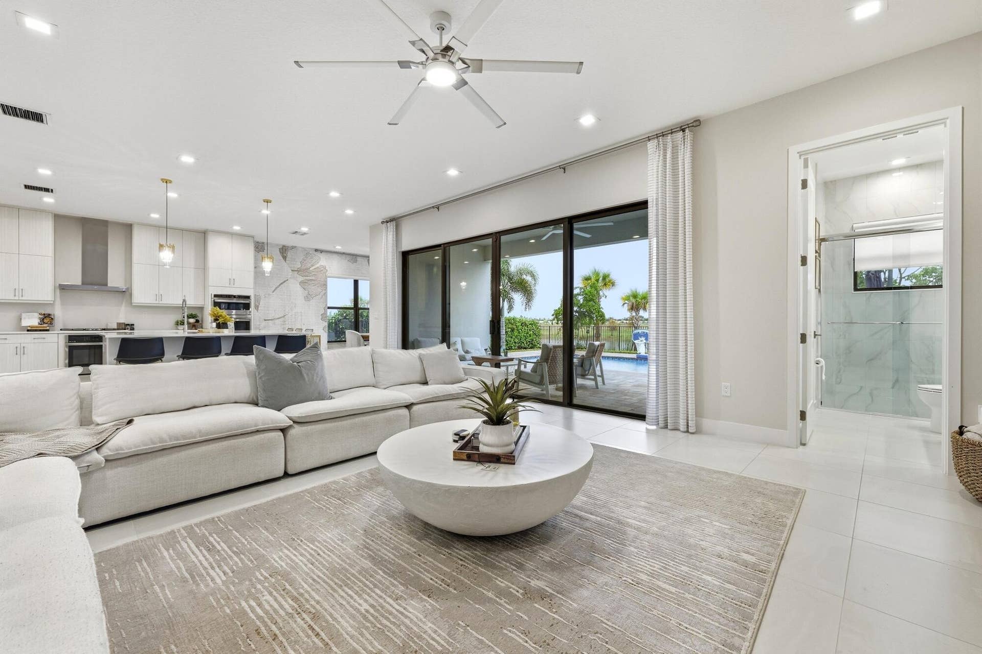 Open concept living area with recessed lighting, ceiling fan, large format tile flooring, and sliding glass doors to the exterior