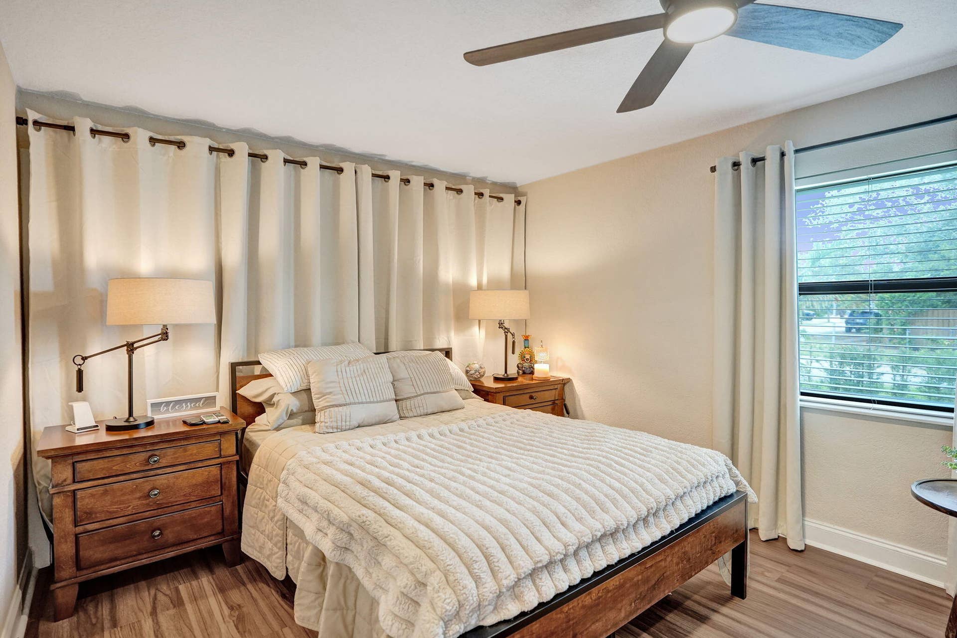 Bedroom featuring wood-finish flooring, a ceiling fan with integrated lighting, and a window with blinds