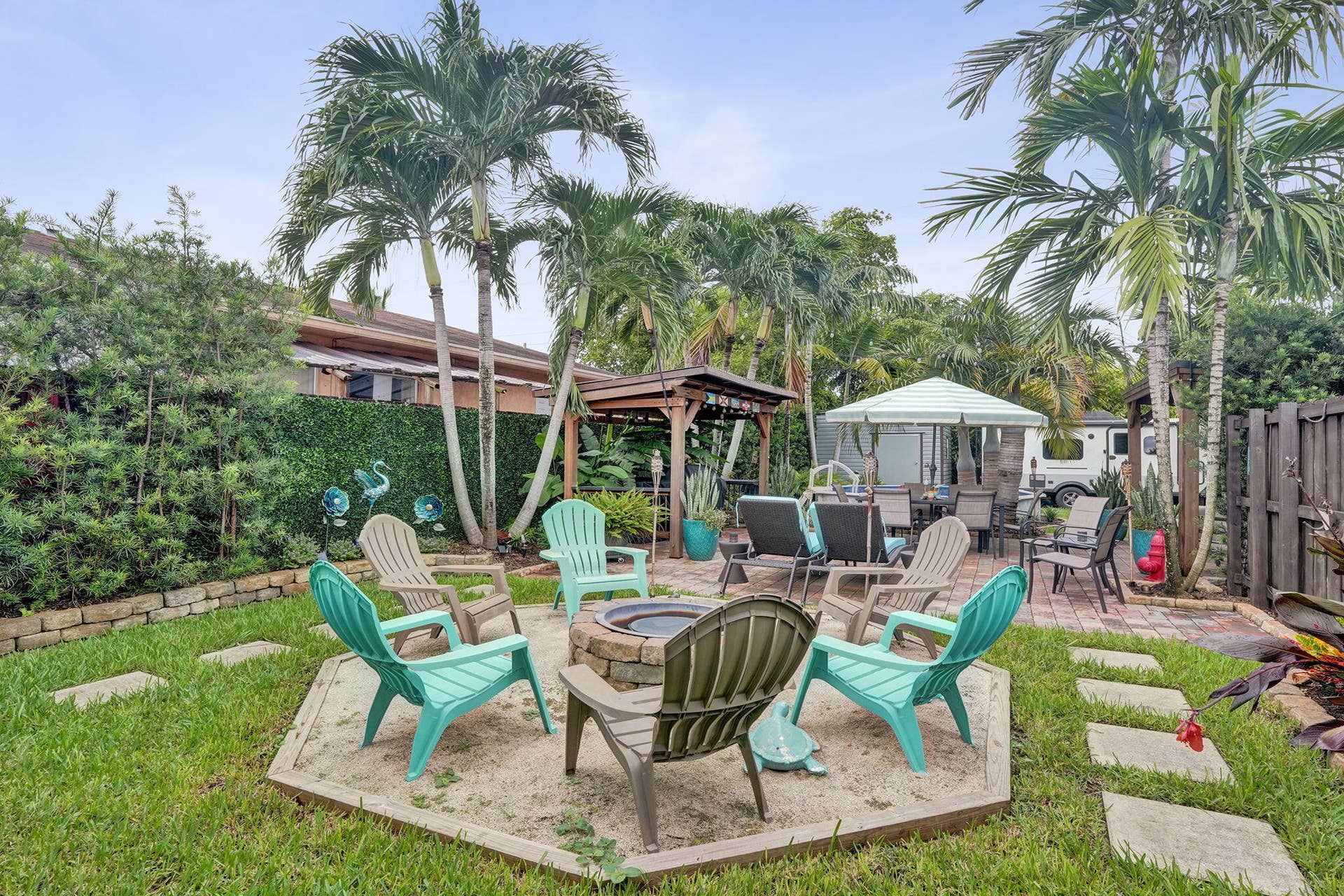 Expansive backyard featuring a stone fire pit, mature palm trees, and a paved patio area