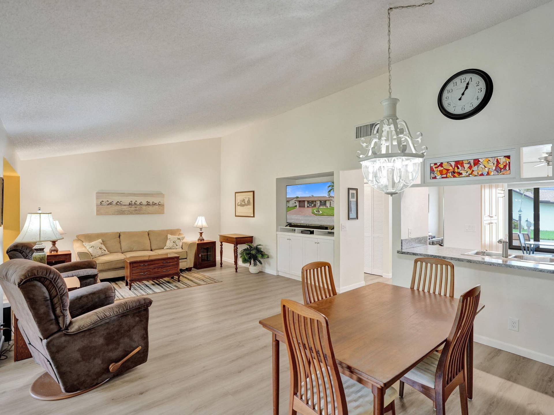 2085 SW 15th Place, Deerfield Beach, FL 33442 Vaulted ceilings, wood-finish flooring, built-in media console, kitchen pass-through with breakfast bar, and a decorative chandelier