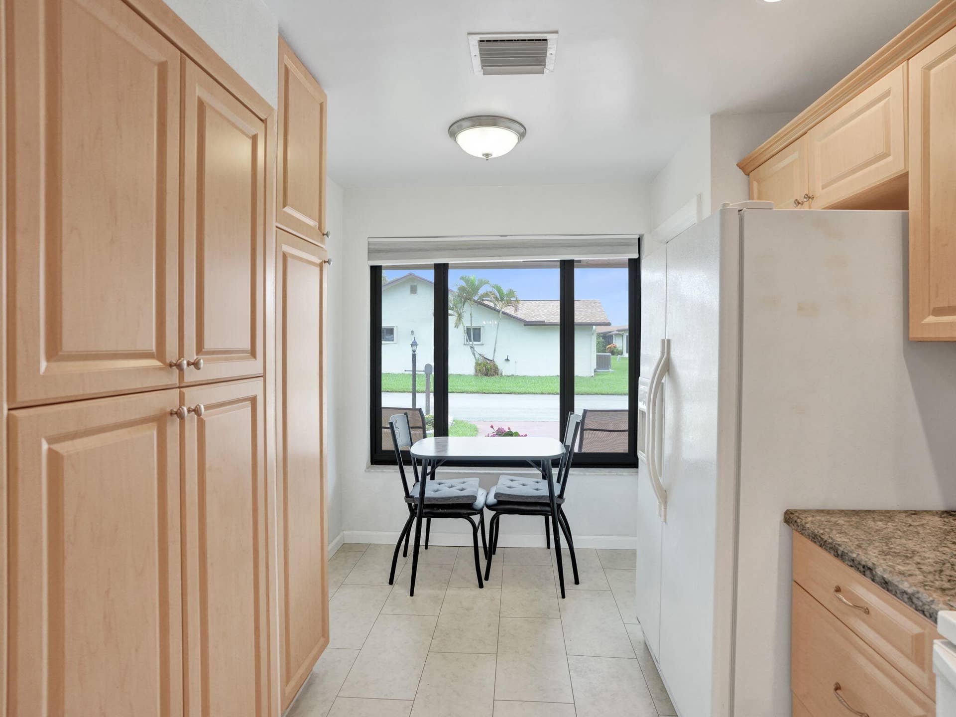 2085 SW 15th Place, Deerfield Beach, FL 33442 Kitchen featuring light wood-finish cabinetry, tile flooring, granite-finish countertops, and a large window
