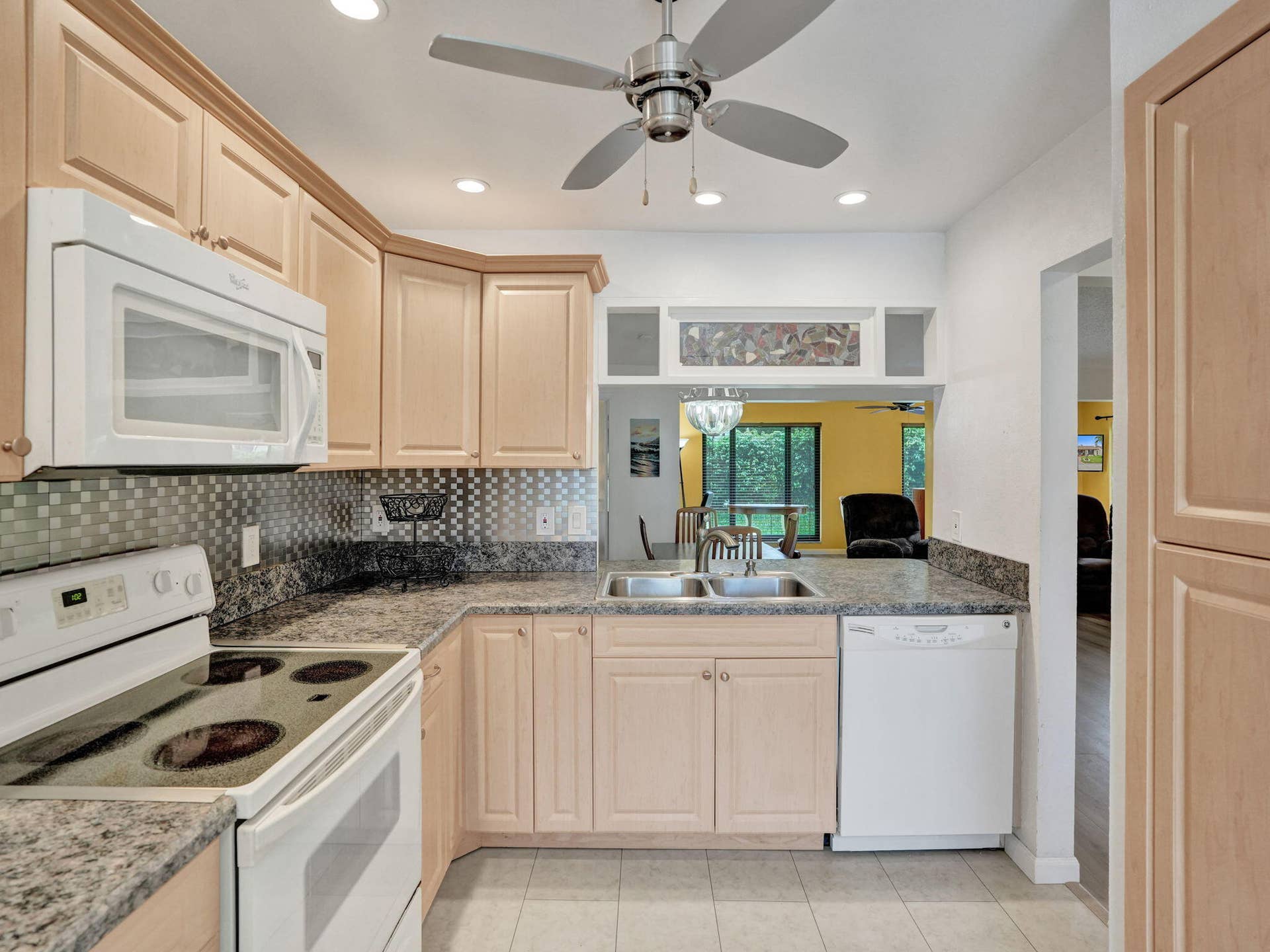 2085 SW 15th Place, Deerfield Beach, FL 33442 Kitchen with light wood-finish cabinetry, granite-style countertops, and a tile backsplash