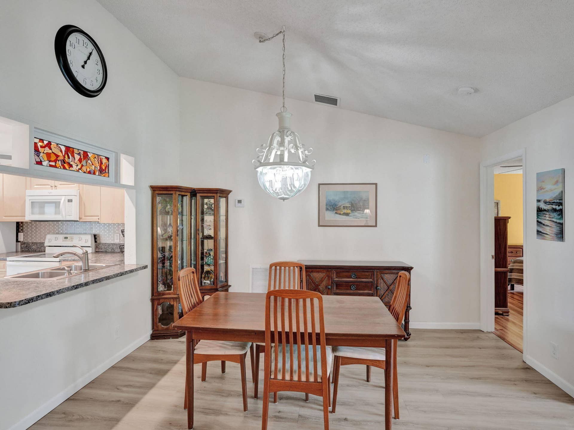 2085 SW 15th Place, Deerfield Beach, FL 33442 Vaulted white ceilings, wood-finish flooring, and a kitchen pass-through with a granite countertop and mosaic tile backsplash