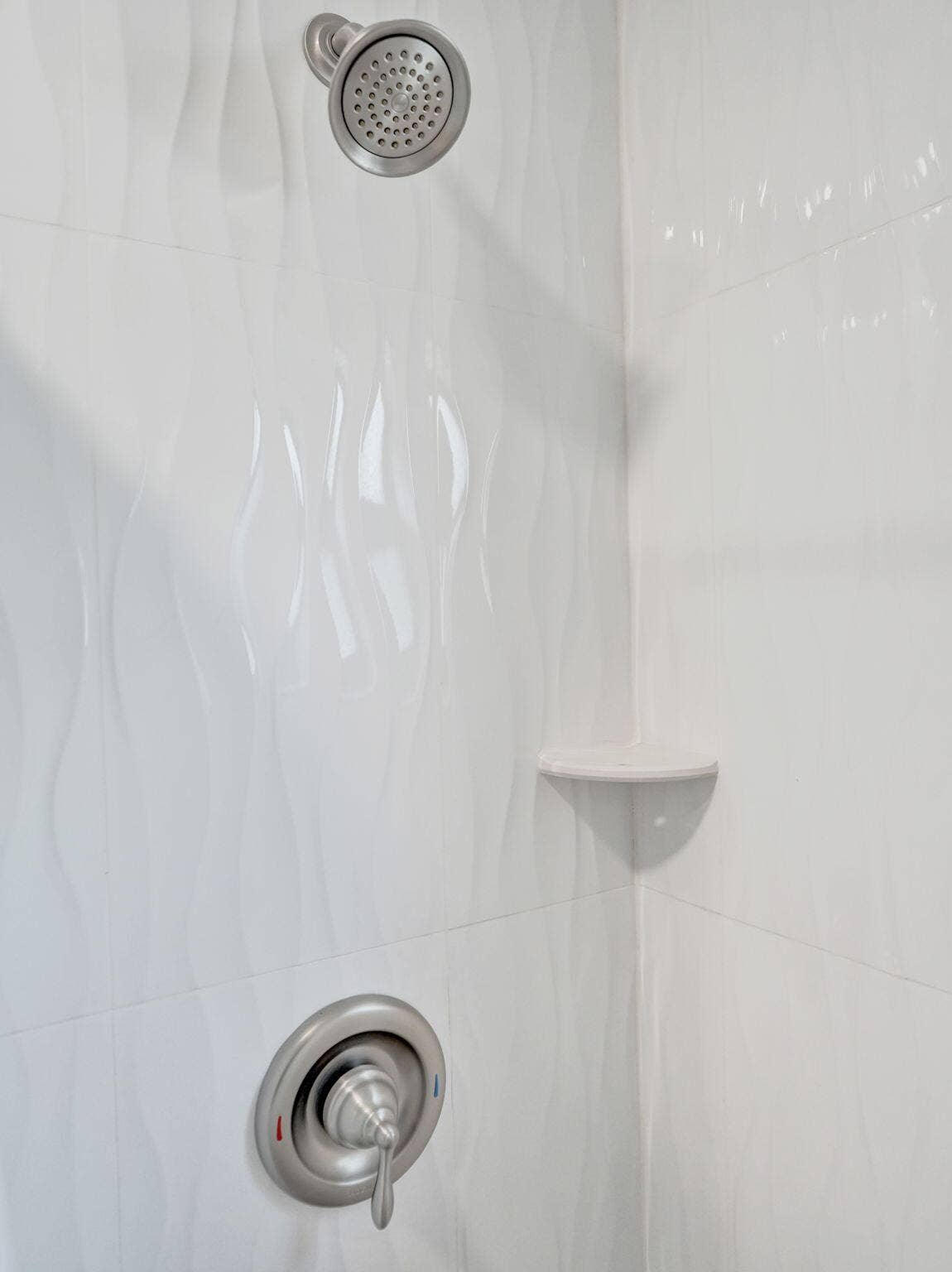 2085 SW 15th Place, Deerfield Beach, FL 33442 Shower featuring textured white tile, a brushed nickel shower head, a coordinating brushed nickel control handle, and a built-in corner shelf
