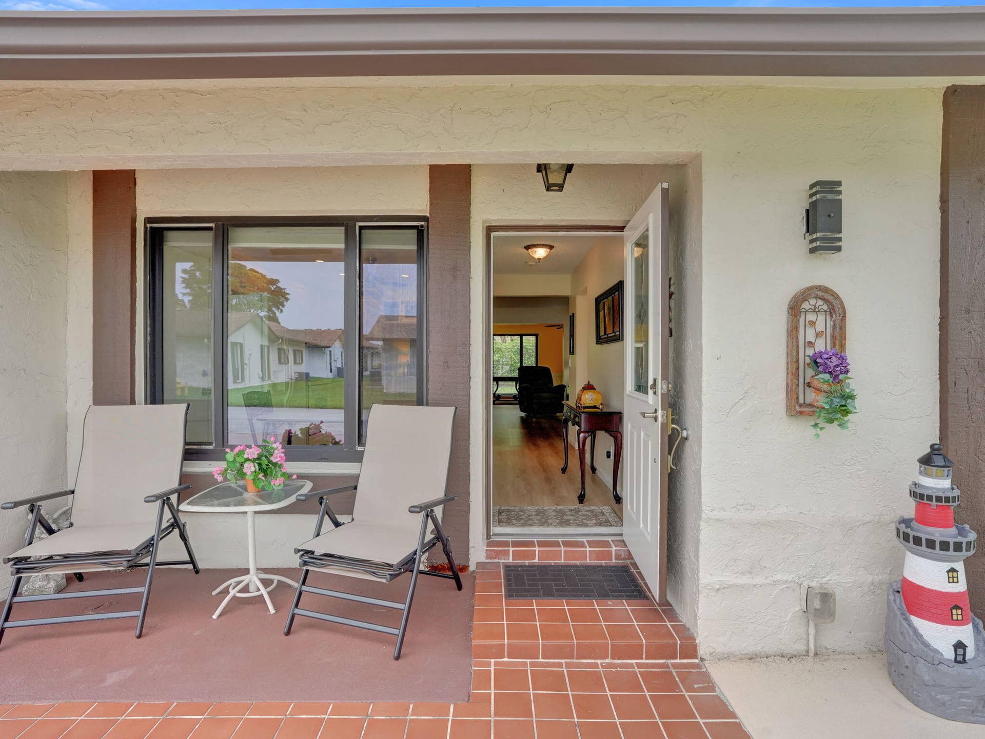 2085 SW 15th Place, Deerfield Beach, FL 33442 Covered entry with terracotta-style tile flooring, exterior lighting fixture, and a white entry door with glass paneling