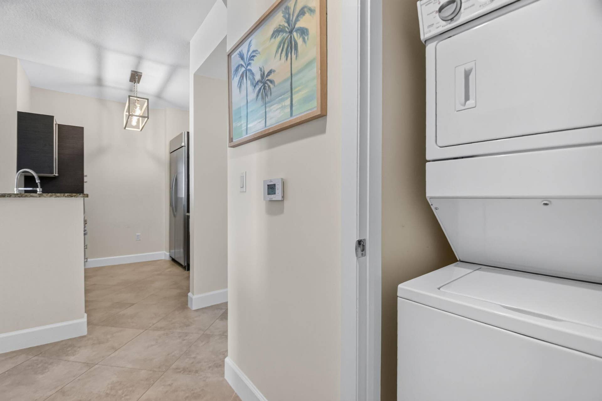 550 OKEECHOBEE Boulevard, #1618, West Palm Beach, West Palm Beach, FL 33401 Stacked laundry appliances, stainless steel refrigerator, tile flooring, built-in cabinetry, and pendant light fixture