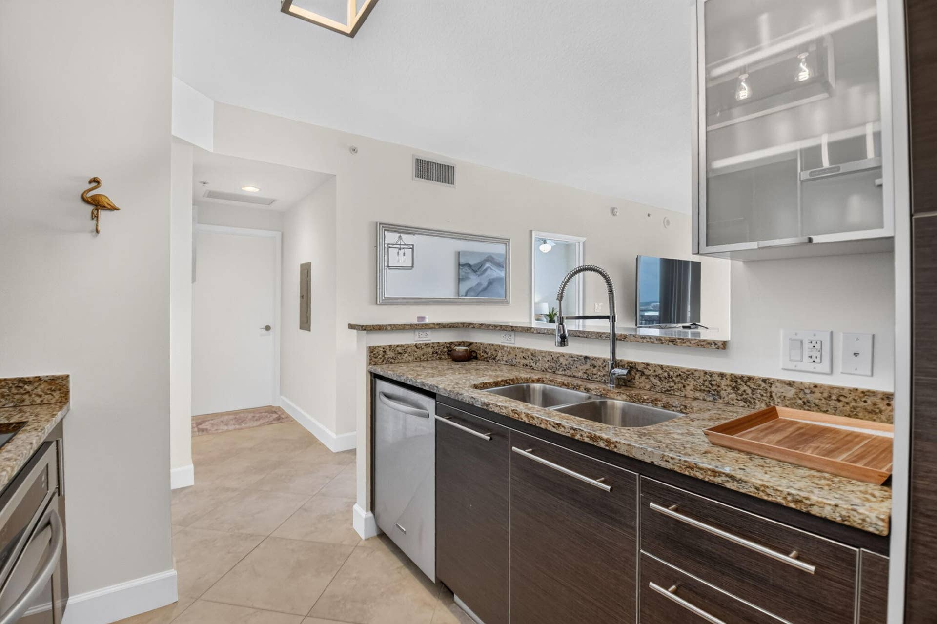 550 OKEECHOBEE Boulevard, #1618, West Palm Beach, West Palm Beach, FL 33401 Kitchen featuring dark wood-finish cabinetry, stainless steel dishwasher, double basin sink with a gooseneck faucet, and light-toned granite countertops
