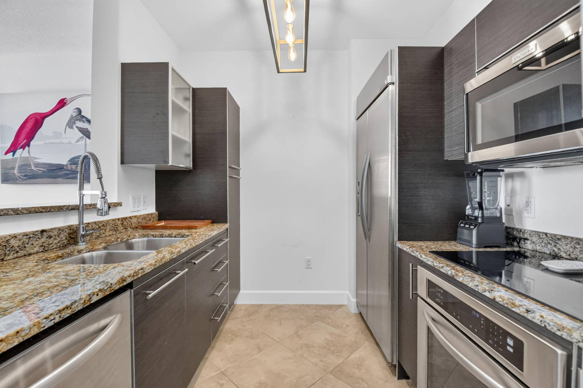 550 OKEECHOBEE Boulevard, #1618, West Palm Beach, West Palm Beach, FL 33401 Galley kitchen featuring dark wood-finish cabinetry, granite countertops, stainless steel appliances, and a double basin sink