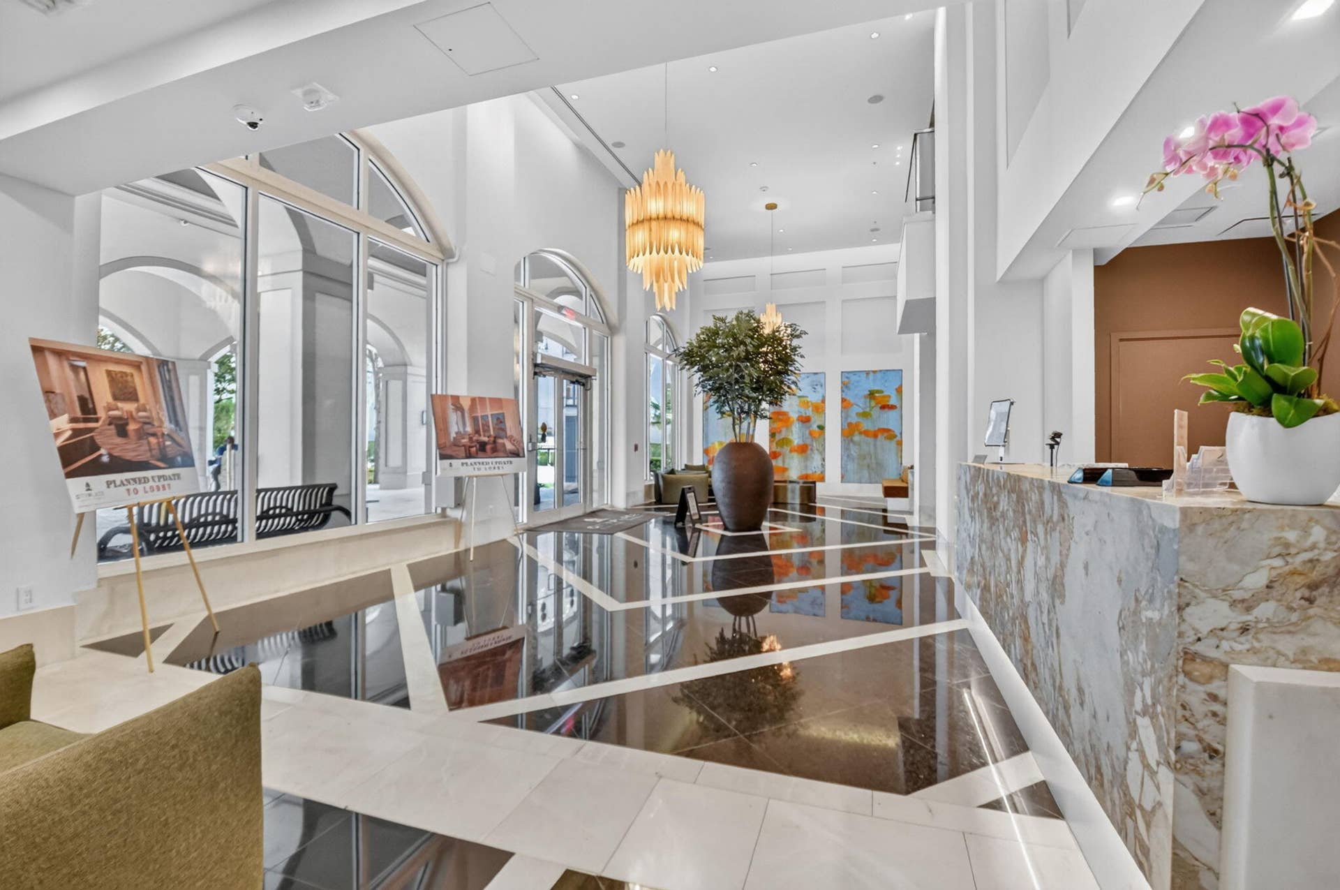 550 OKEECHOBEE Boulevard, #1618, West Palm Beach, West Palm Beach, FL 33401 Grand entry featuring a varied tile floor pattern, high ceilings, large arched windows, a built-in reception desk with stone-finish cladding, and an ornate multi-tier chandelier