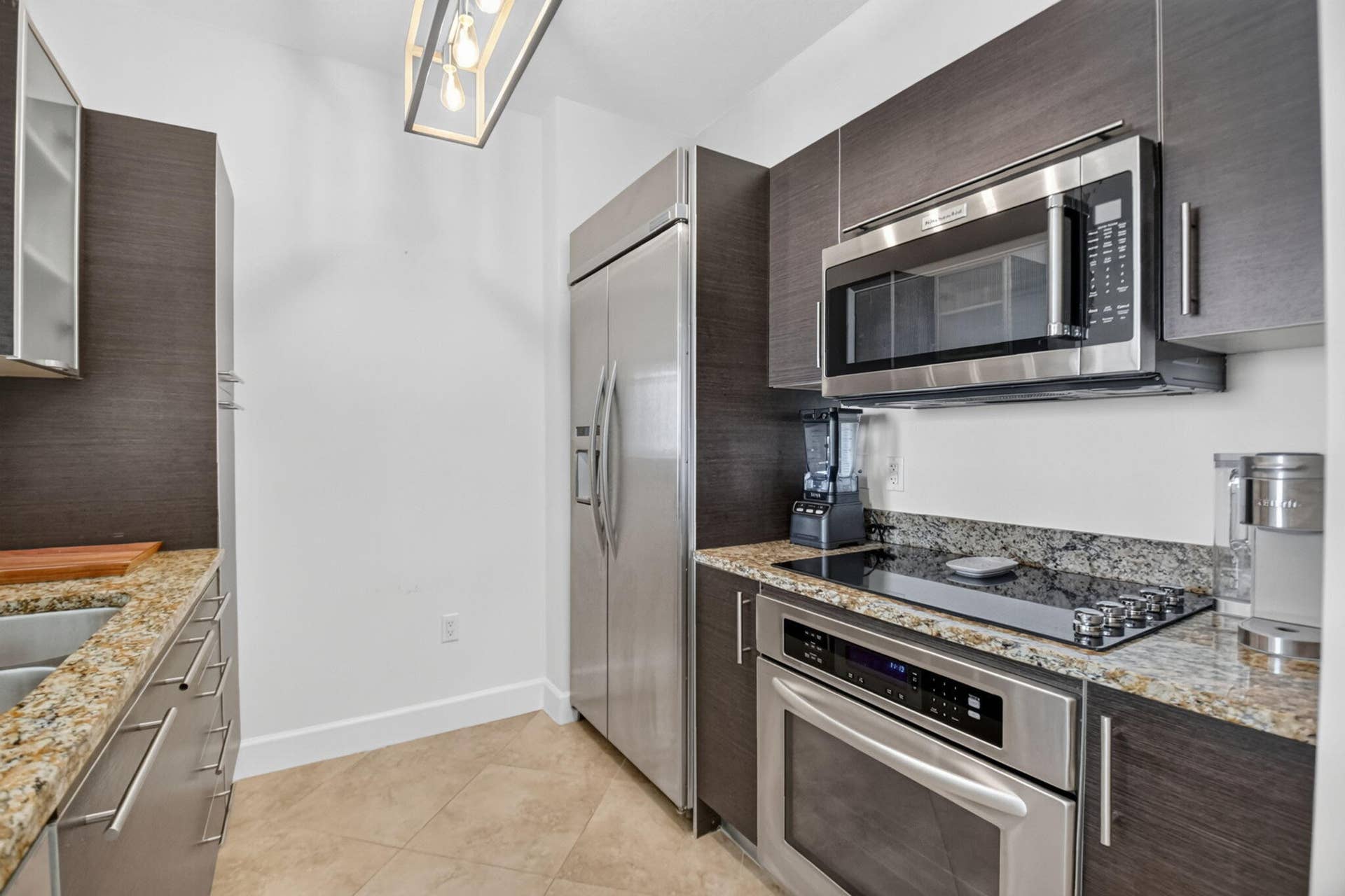 550 OKEECHOBEE Boulevard, #1618, West Palm Beach, West Palm Beach, FL 33401 Kitchen featuring stainless steel appliances, dark wood-finish cabinetry, light-toned granite countertops, and tile flooring