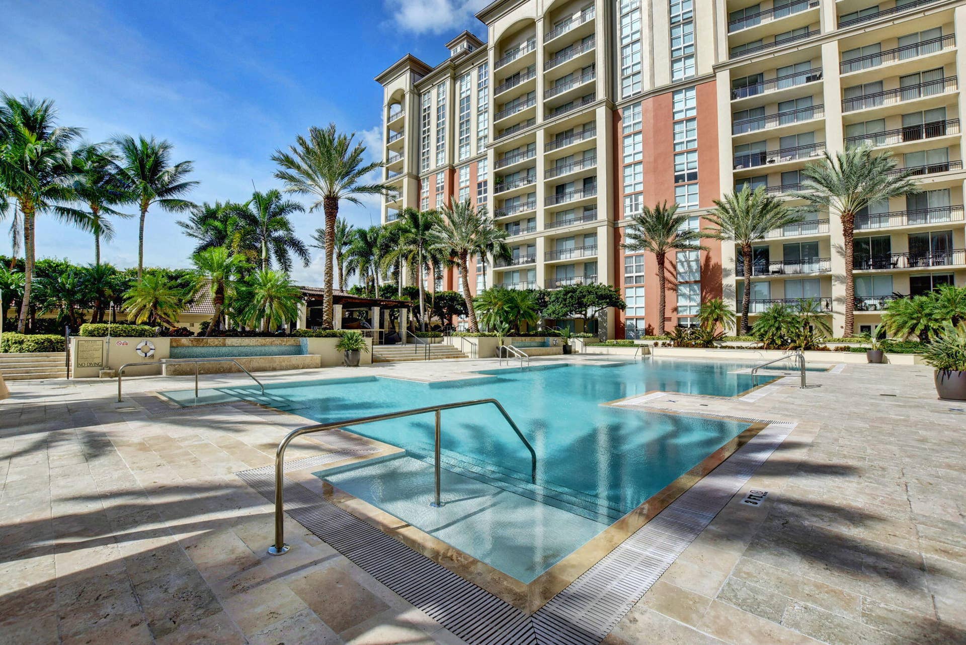 550 OKEECHOBEE Boulevard, #1618, West Palm Beach, West Palm Beach, FL 33401 Multi-story building with multiple balconies, expansive swimming pool, integrated spa, surrounding paver patio, and mature palm trees