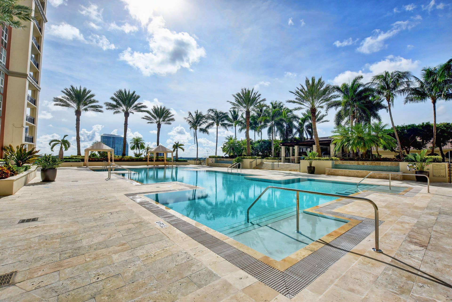 550 OKEECHOBEE Boulevard, #1618, West Palm Beach, West Palm Beach, FL 33401 Expansive outdoor pool deck featuring a swimming pool, multiple palm trees, two cabanas, and integrated planters