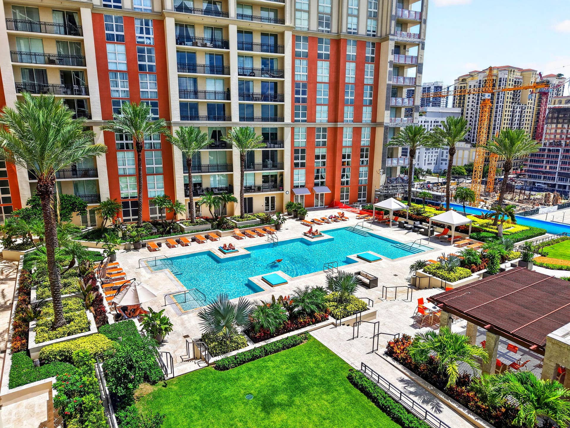550 OKEECHOBEE Boulevard, #1618, West Palm Beach, West Palm Beach, FL 33401 Expansive outdoor pool deck featuring a swimming pool, multiple lounge areas, and lush landscaping with mature palm trees