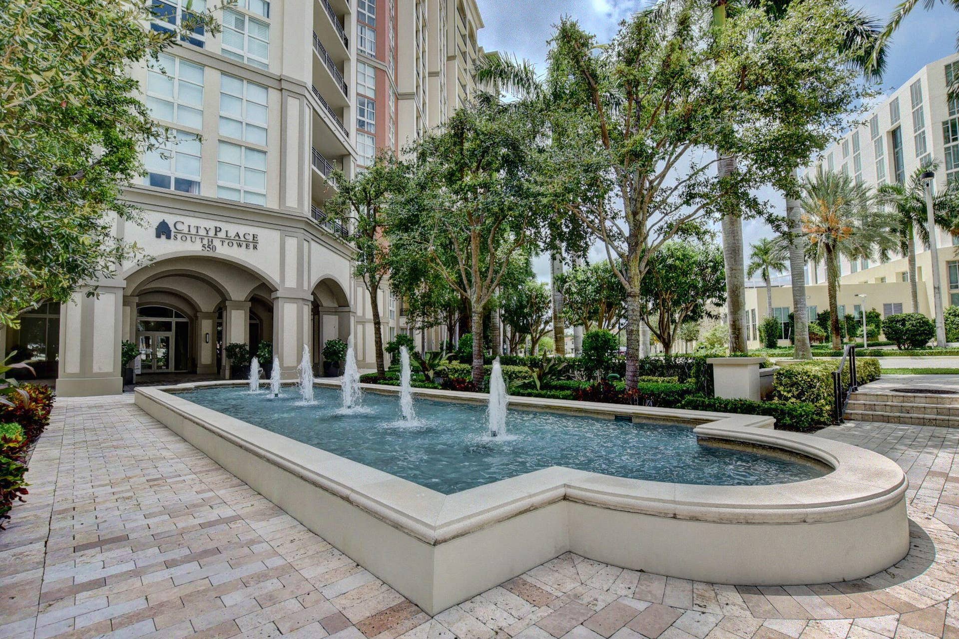 550 OKEECHOBEE Boulevard, #1618, West Palm Beach, West Palm Beach, FL 33401 Building exterior featuring an arched entryway, established landscaping, and a decorative water feature