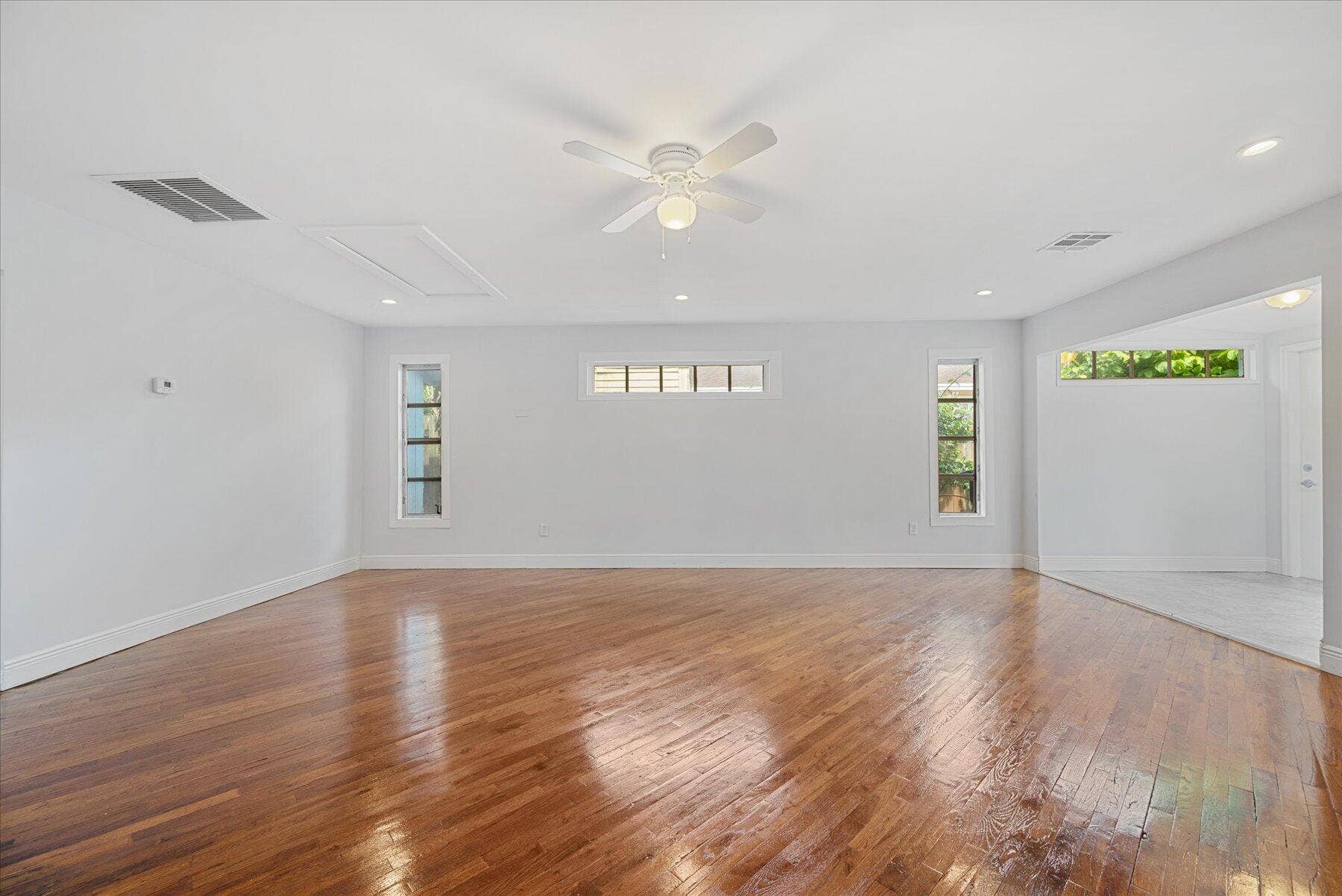 714 W Lakewood Road, #B, West Palm Beach, West Palm Beach, FL 33405 Polished wood-finish flooring, recessed lighting, white ceiling fan, multiple windows, and a doorway with tile flooring