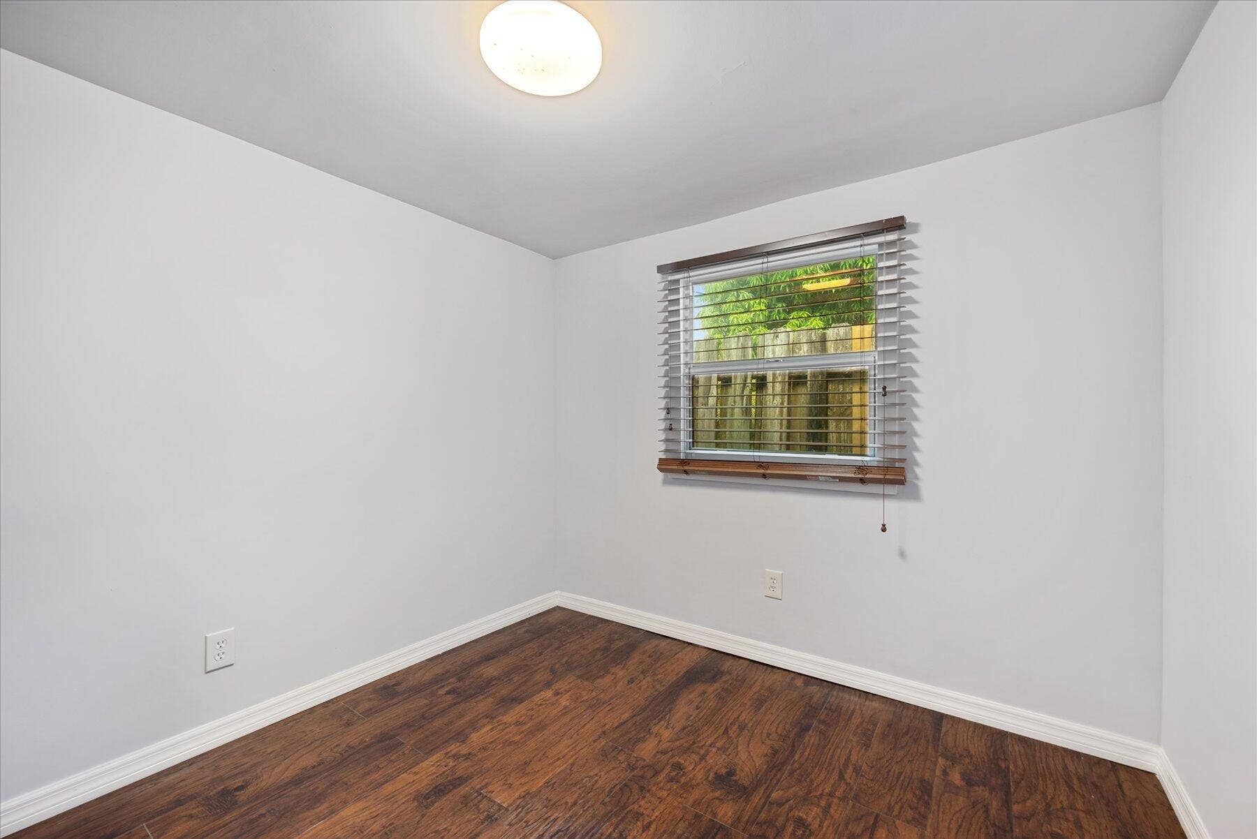 714 W Lakewood Road, #B, West Palm Beach, West Palm Beach, FL 33405 Wood-finish flooring, white baseboards, and a window with blinds