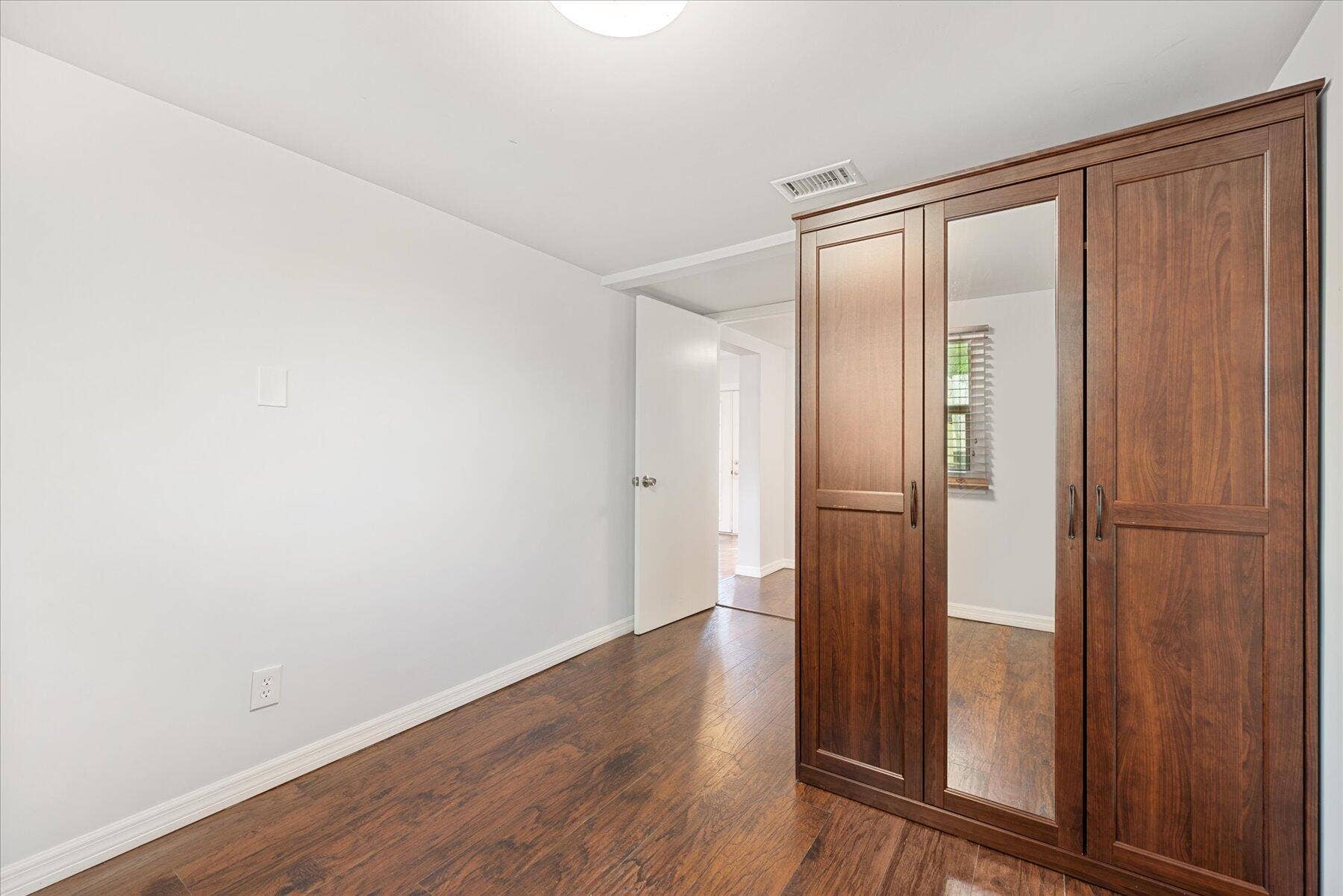 714 W Lakewood Road, #B, West Palm Beach, West Palm Beach, FL 33405 Wood-finish flooring, white walls, and a built-in wardrobe with mirrored doors