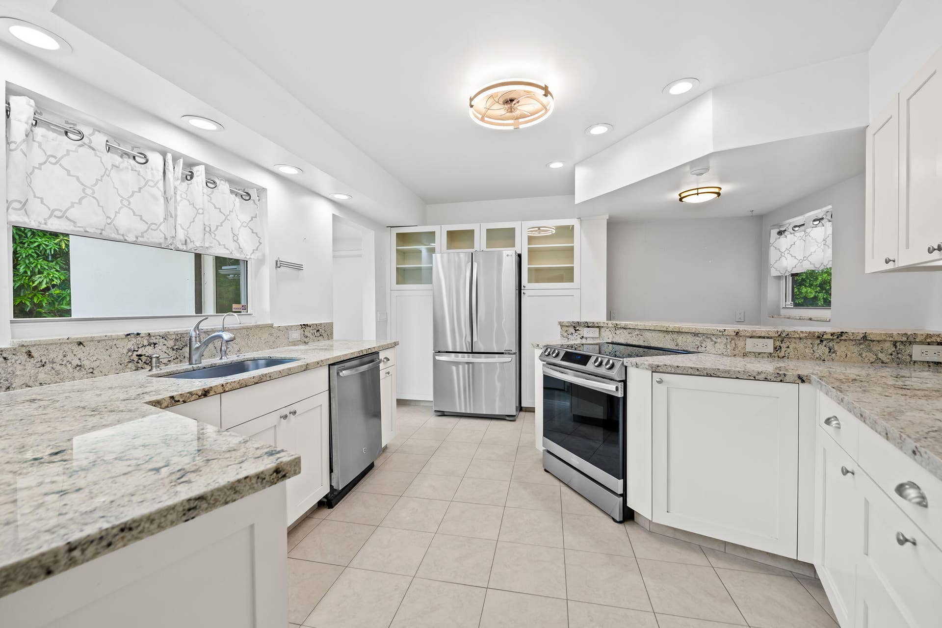 1705 NE 26TH Avenue, Fort Lauderdale, FL 33305 White cabinetry, stainless steel appliances, light-toned stone countertops, recessed lighting, and tile flooring