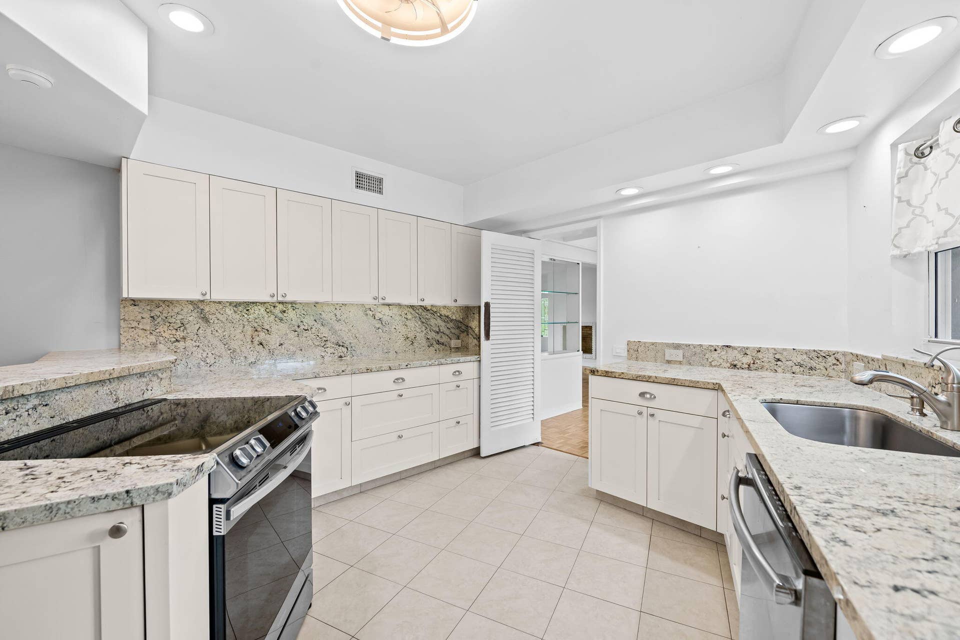 1705 NE 26TH Avenue, Fort Lauderdale, FL 33305 Kitchen featuring extensive light-toned cabinetry, granite countertops, stainless steel appliances, a stainless steel sink, and tiled flooring