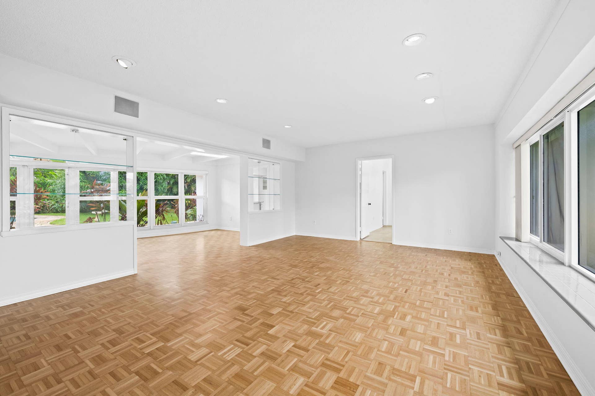 1705 NE 26TH Avenue, Fort Lauderdale, FL 33305 Recessed lighting, wood-finish parquet flooring, white walls, built-in display shelving, and large windows