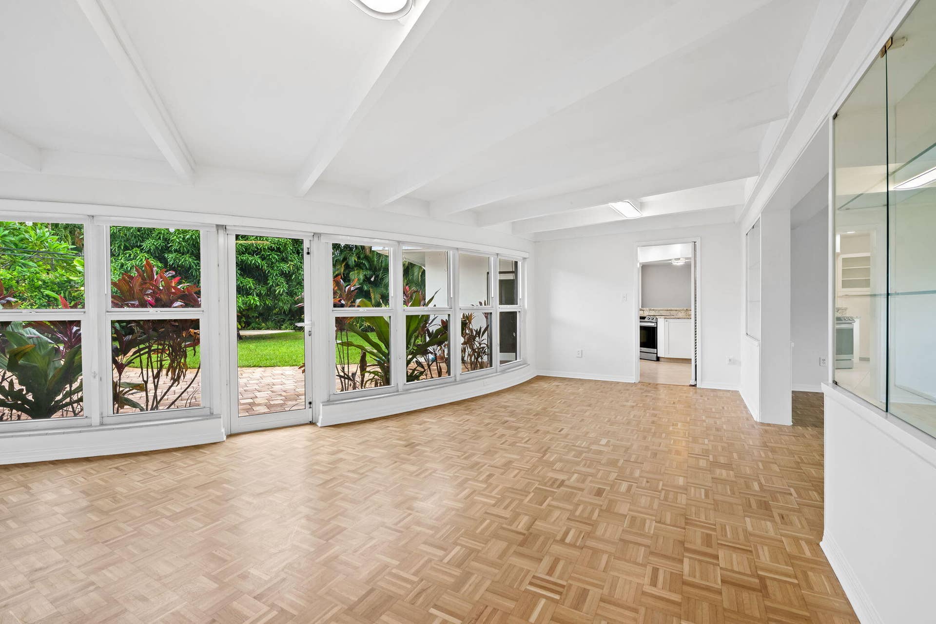 1705 NE 26TH Avenue, Fort Lauderdale, FL 33305 Parquet flooring, white coffered ceilings, built-in display cabinetry, and a full wall of windows with sliding glass door access to the exterior