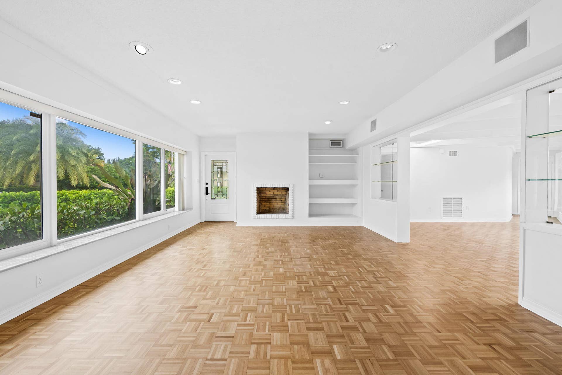 1705 NE 26TH Avenue, Fort Lauderdale, FL 33305 Parquet wood flooring, a fireplace, recessed lighting, built-in shelving, and large windows