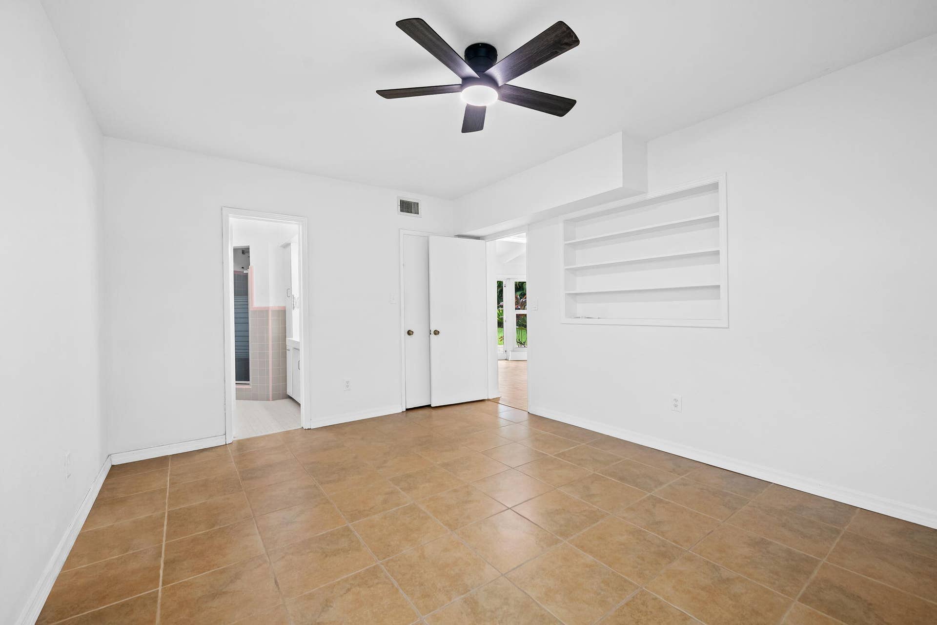 1705 NE 26TH Avenue, Fort Lauderdale, FL 33305 Neutral-toned tile flooring, built-in shelving, and a ceiling fan with integrated lighting