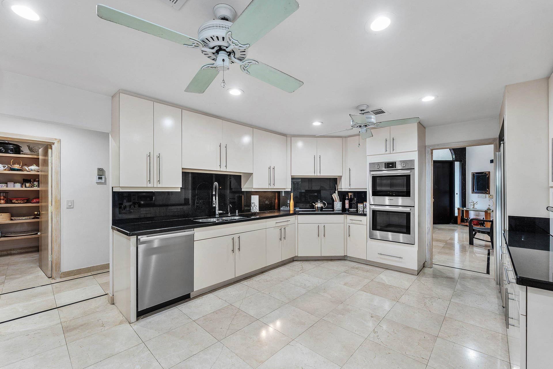 56 NORTHWOODS Lane, Boynton Beach, FL 33436 Kitchen featuring extensive cabinetry, stainless steel appliances, black countertops, and a built-in pantry