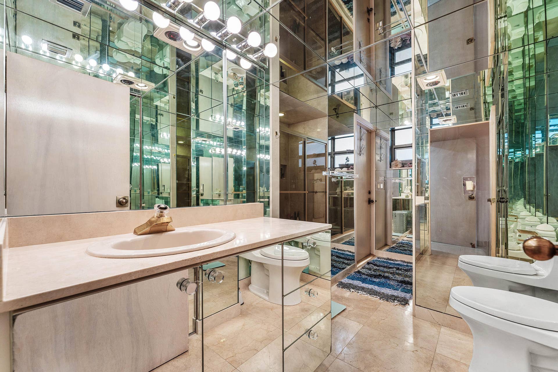 56 NORTHWOODS Lane, Boynton Beach, FL 33436 Mirrored wall finishes throughout, vanity with an integrated sink and light-toned countertop, vanity lighting fixture, and a toilet with an adjacent bidet