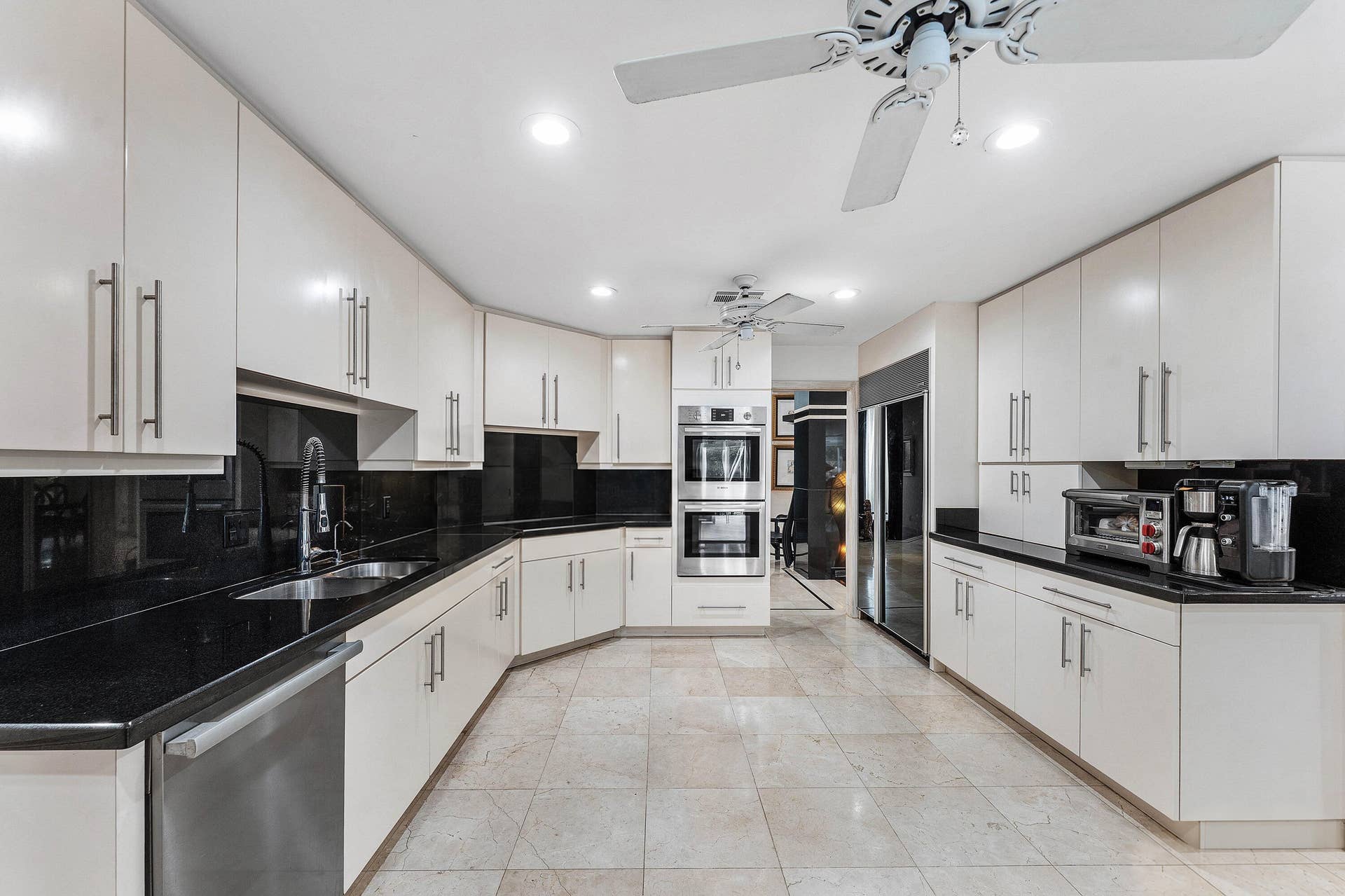 56 NORTHWOODS Lane, Boynton Beach, FL 33436 Expansive kitchen featuring abundant white cabinetry, black countertops, stainless steel appliances including double wall ovens, integrated wine cooler, and tile flooring